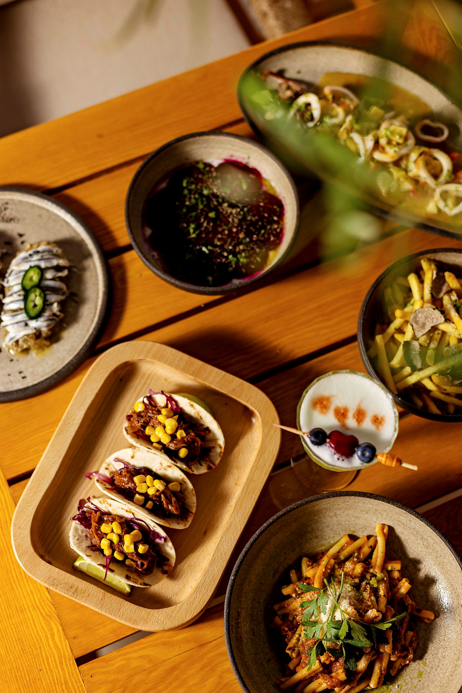 En treflate med et utvalg av forskjellige retter, inkludert tacos, pastarett og drikke. (AI-generert tekst)