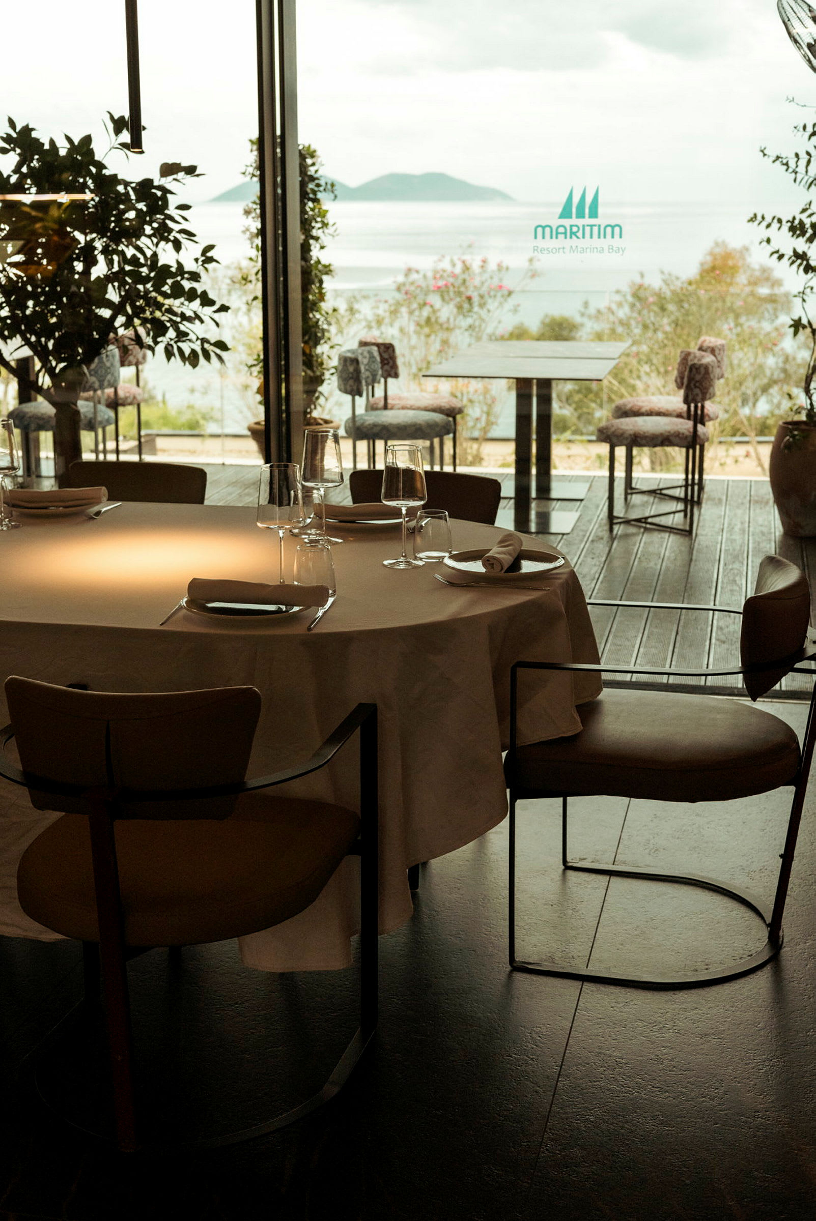 Et bord med duk og glass på en restaurant med utsikt over havet. (AI-generert tekst)