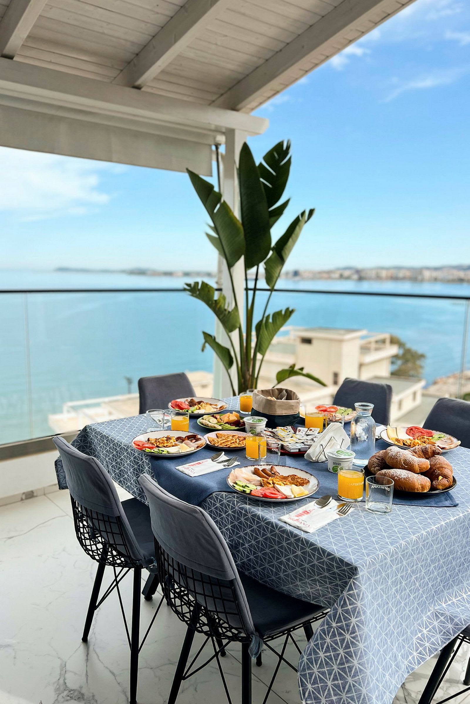 Et dekket bord med frokost på en terrasse med utsikt over havet. (AI-generert tekst)