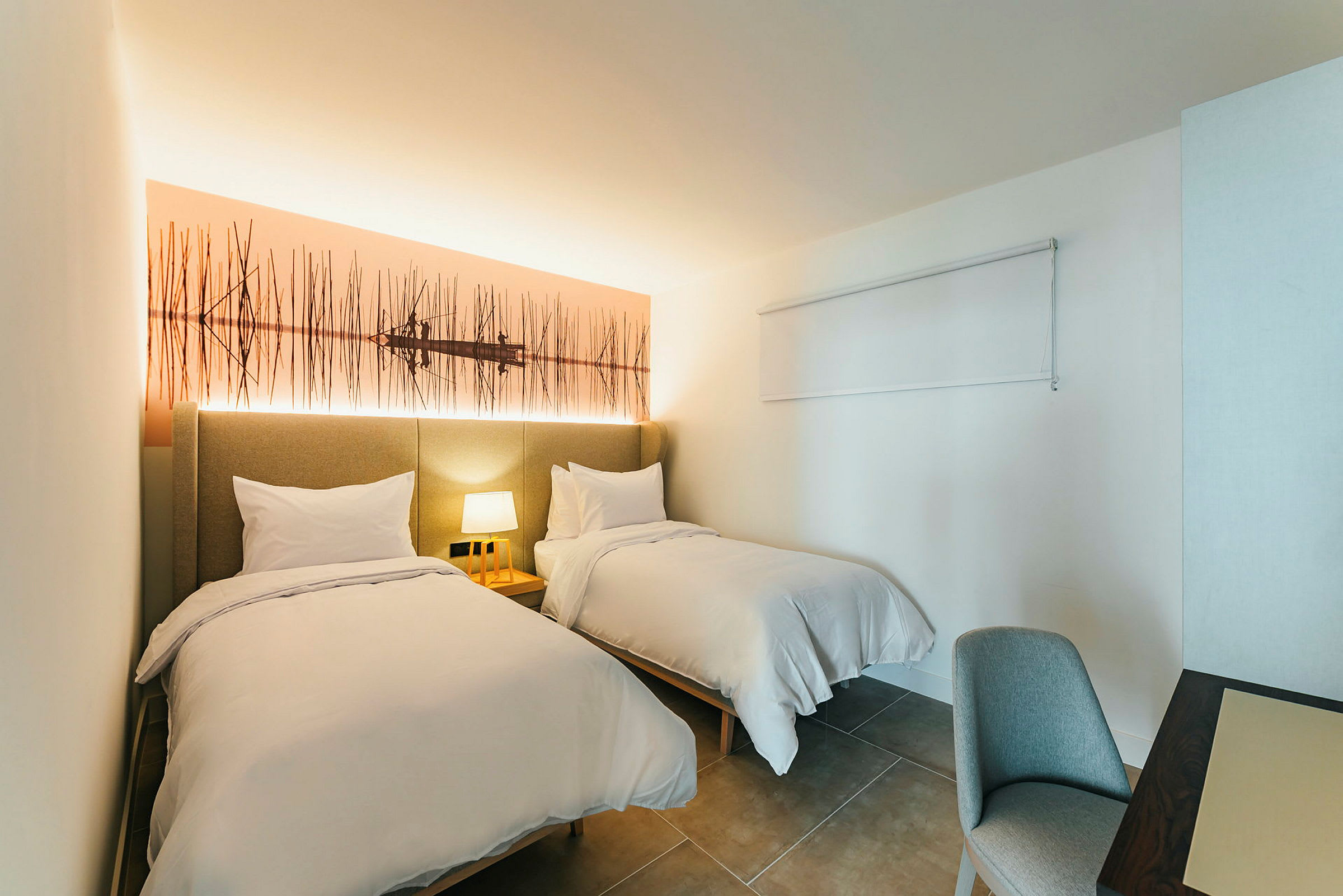 Et hotellrom med to enkeltsenger og en nattlampe. (AI-generert tekst)