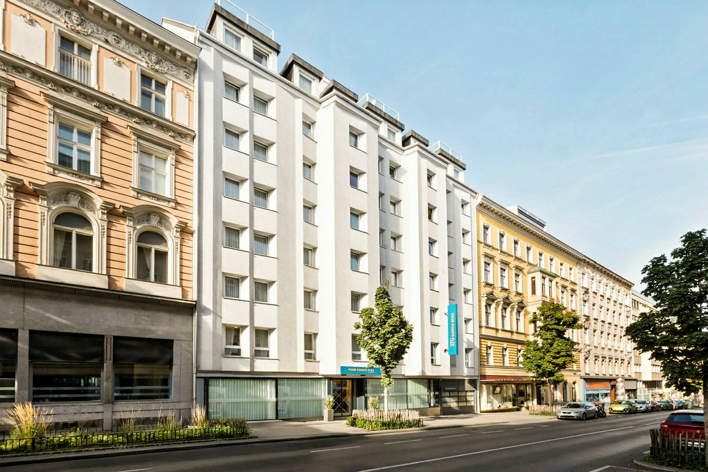 En bygate med bygninger fra ulike tiår, inkludert et hotell med hvit fasade. (AI-generert tekst)