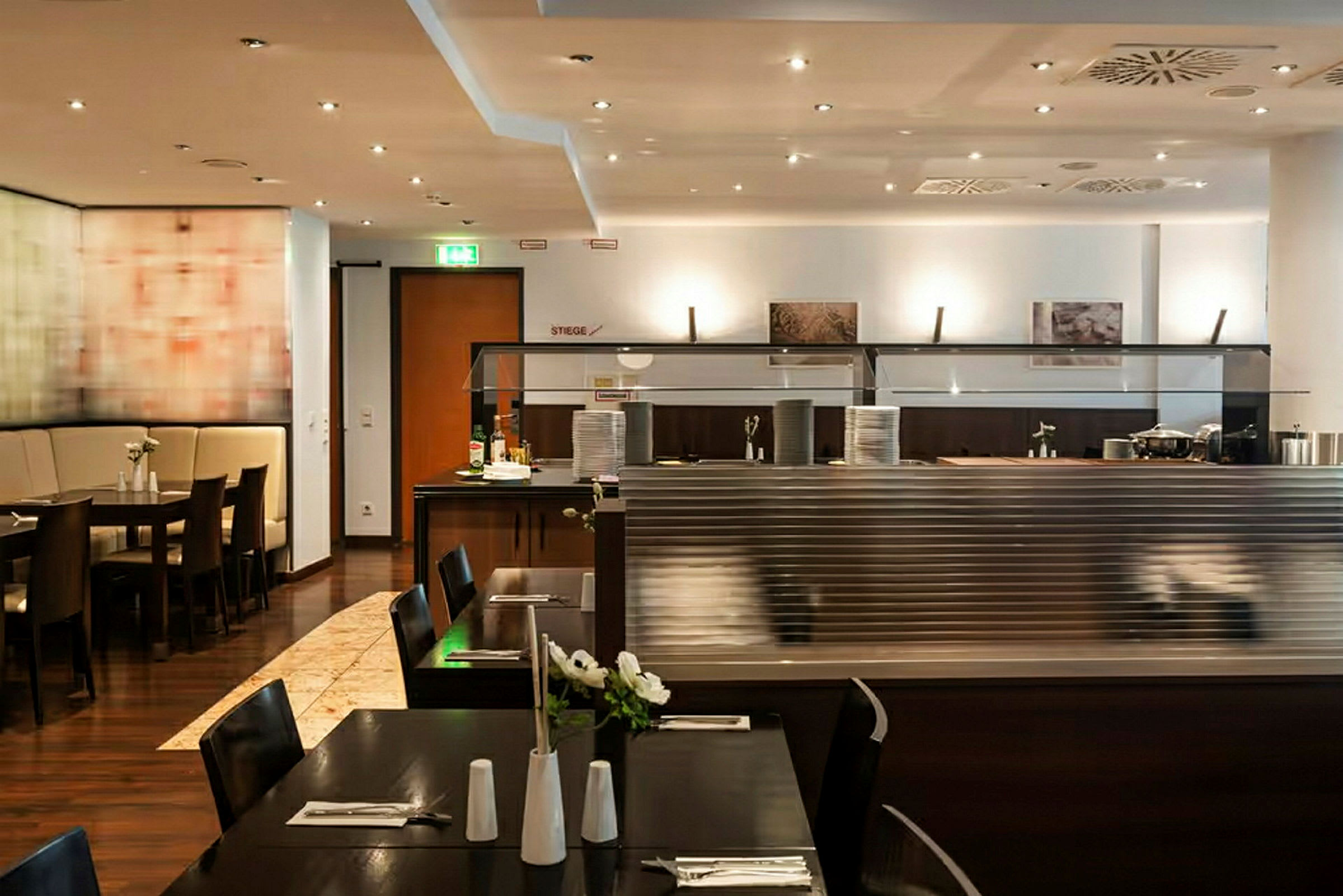 Interiør av en restaurant med mørke trebord, stoler og en buffet. (AI-generert tekst)