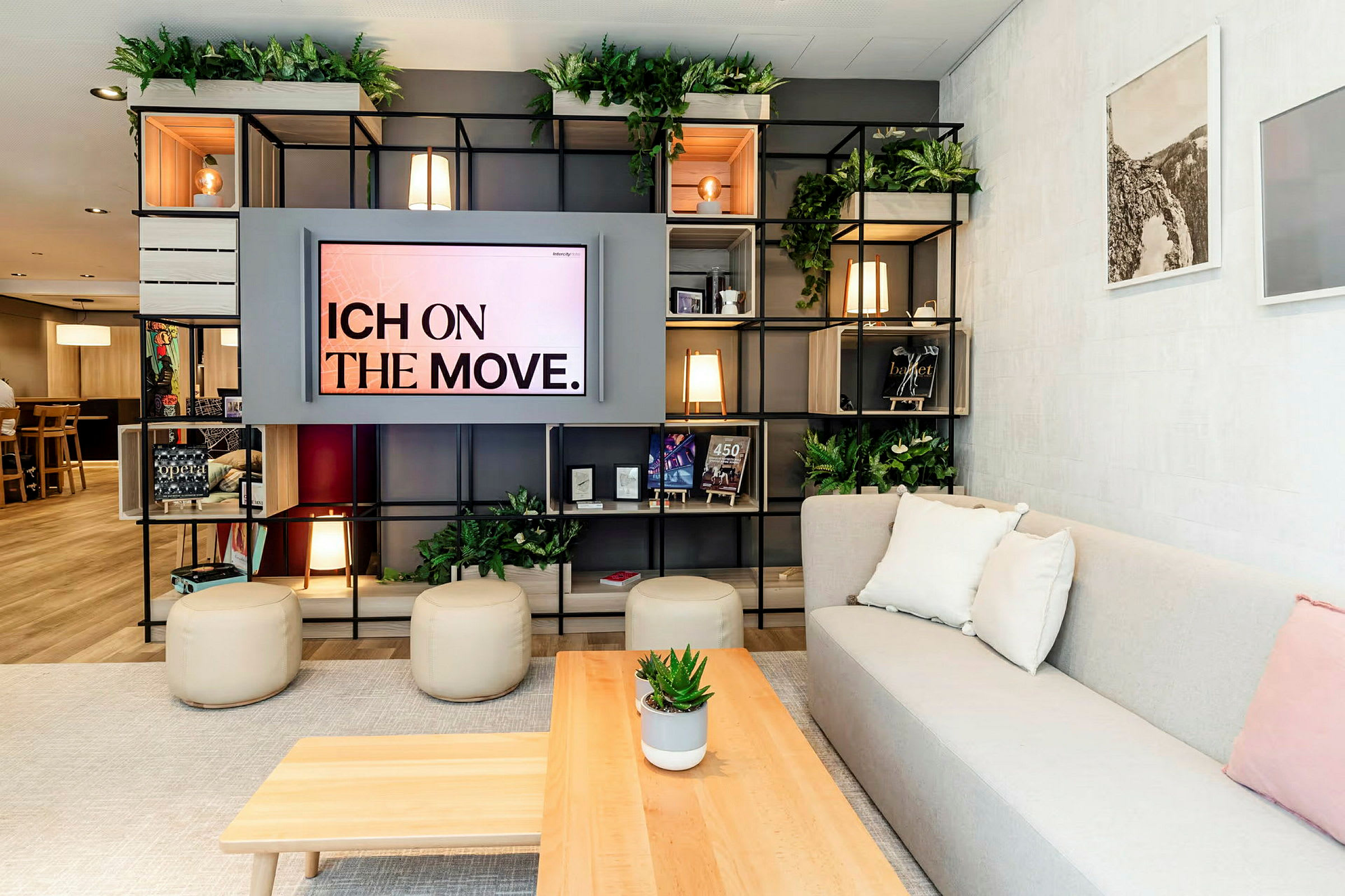 Et moderne stuerom med hyller fylt med gjenstander og blomsterdekorasjoner, en sofa med puter, og et bord med en potteplante. (AI-generert tekst)