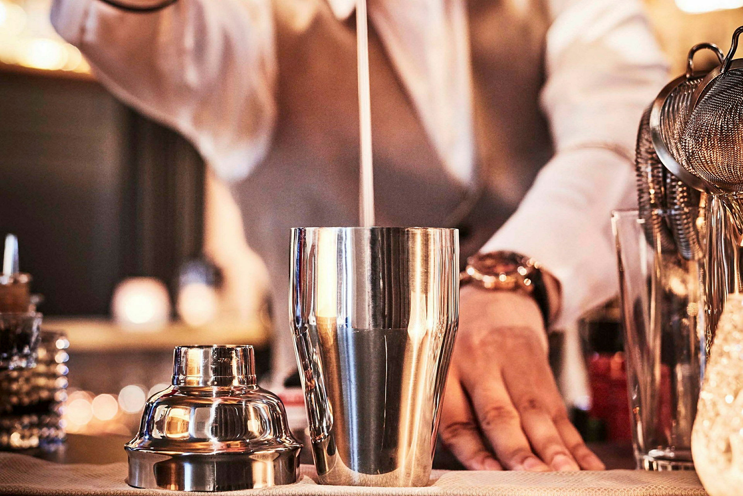 En bartender lager en cocktail i en metallcocktail-shaker. (AI-generert tekst)