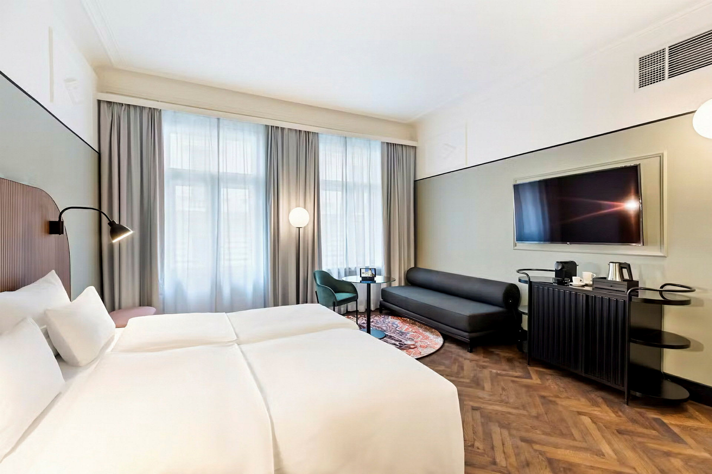 Hotellrom med dobbeltseng, sofa, lenestol og TV. (AI-generert tekst)