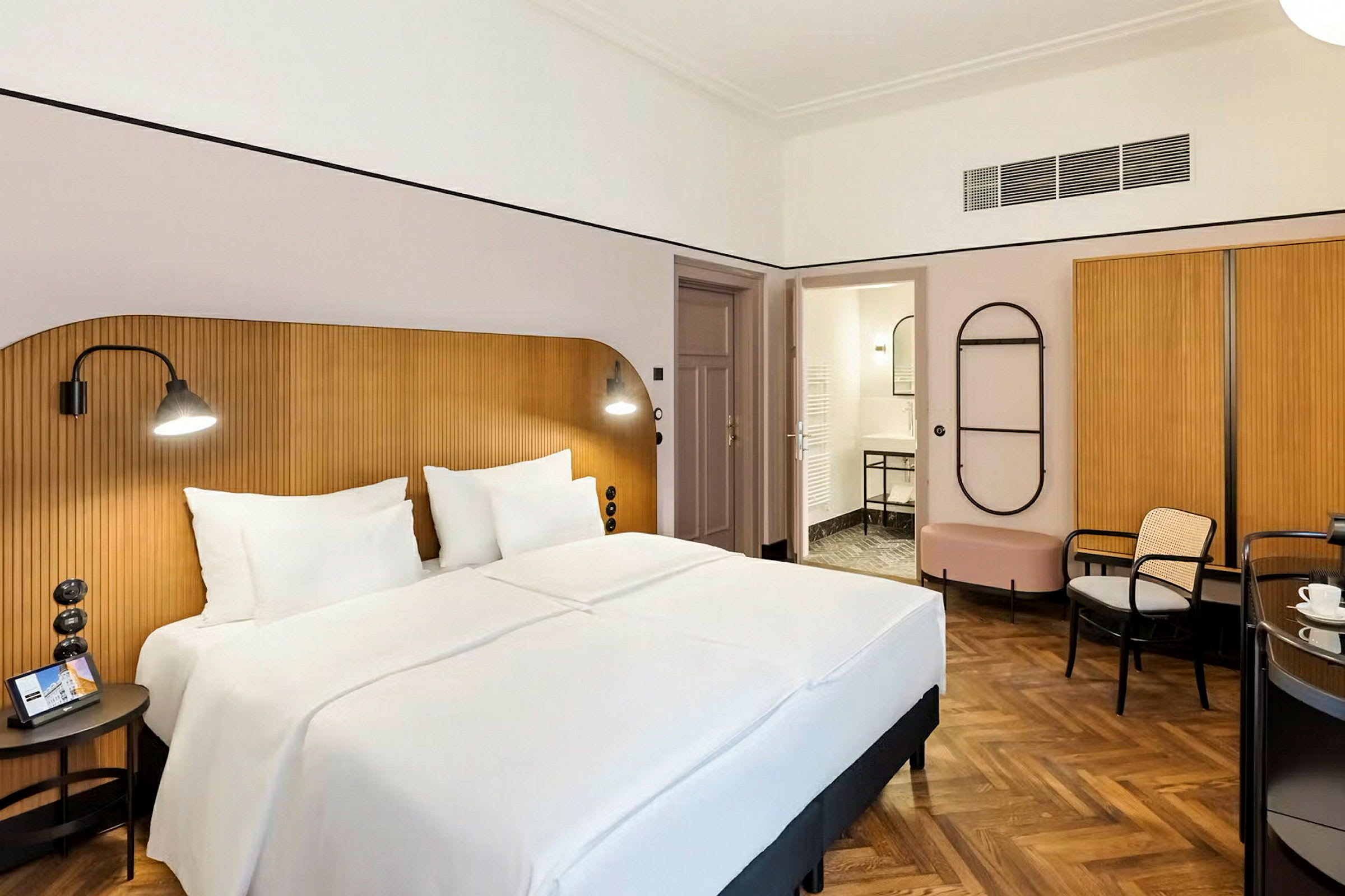 Hotellrom med en dobbeltseng, trepanel bak sengen og et bad i bakgrunnen. (AI-generert tekst)