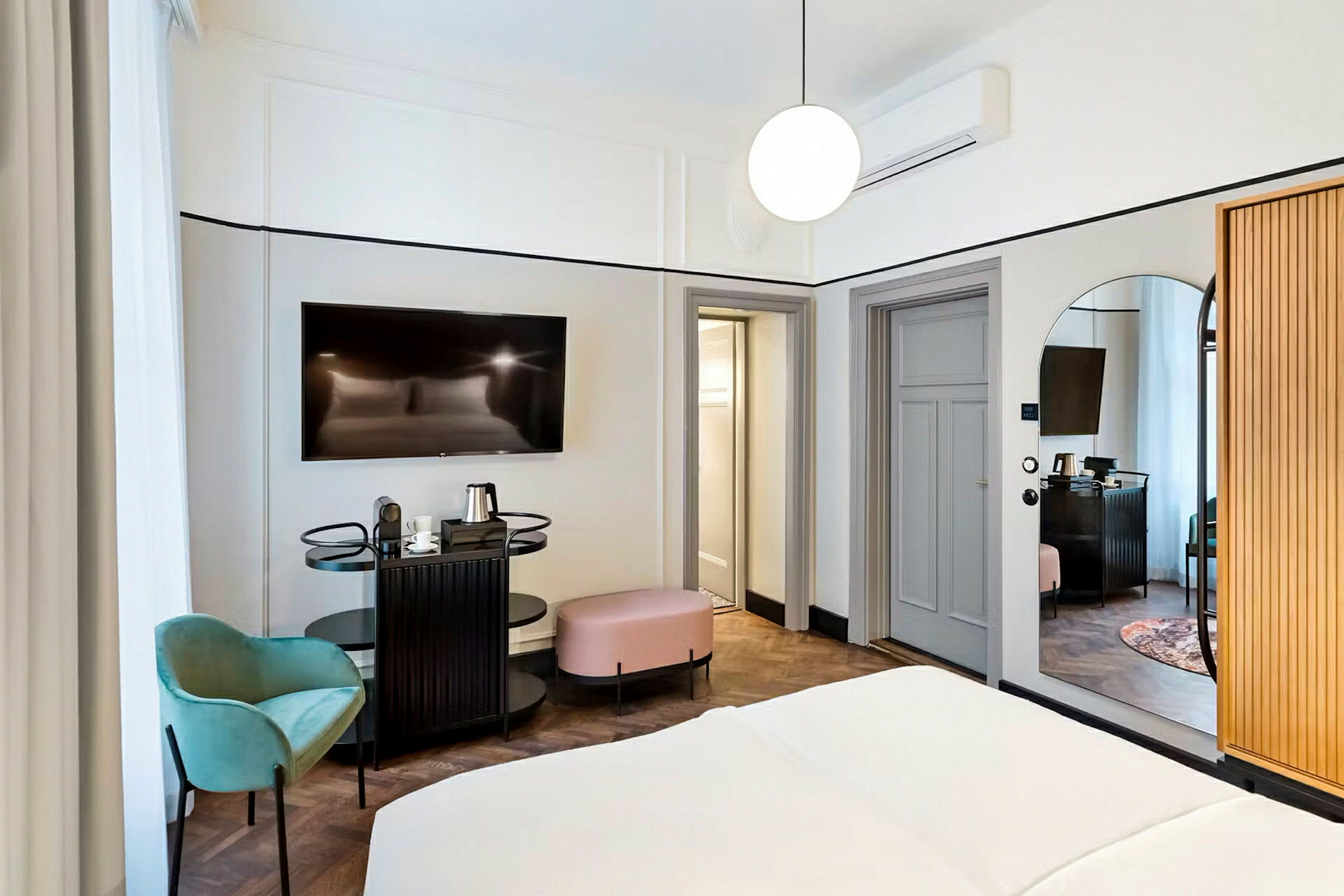 Et hotellrom med en seng, en flatskjerm-TV, mindre sittemøbler og en vannkoker på en stasjon. (AI-generert tekst)