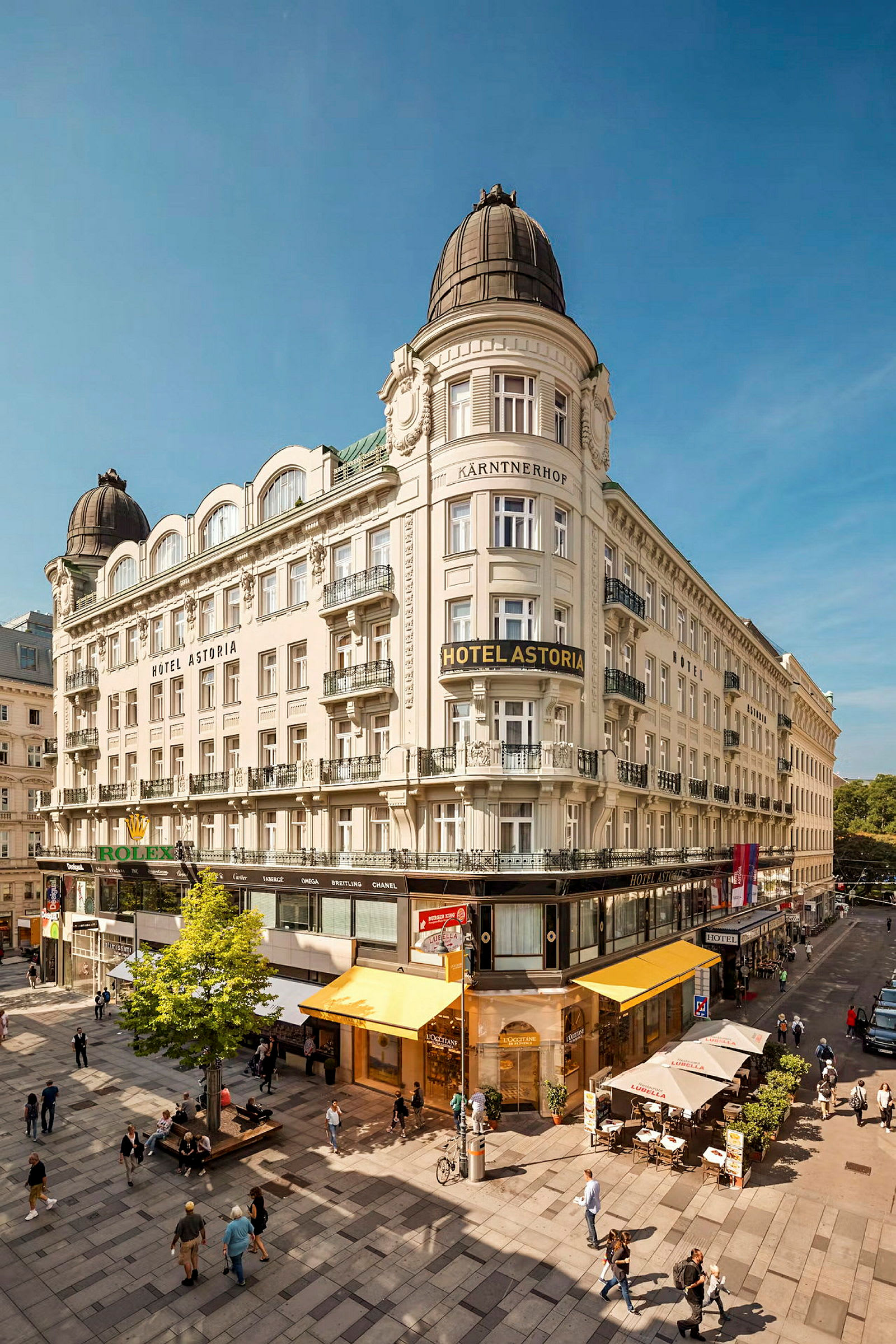 Bilde av et hotell med klassisk arkitektur, plassert ved en livlig bygateg. (AI-generert tekst)