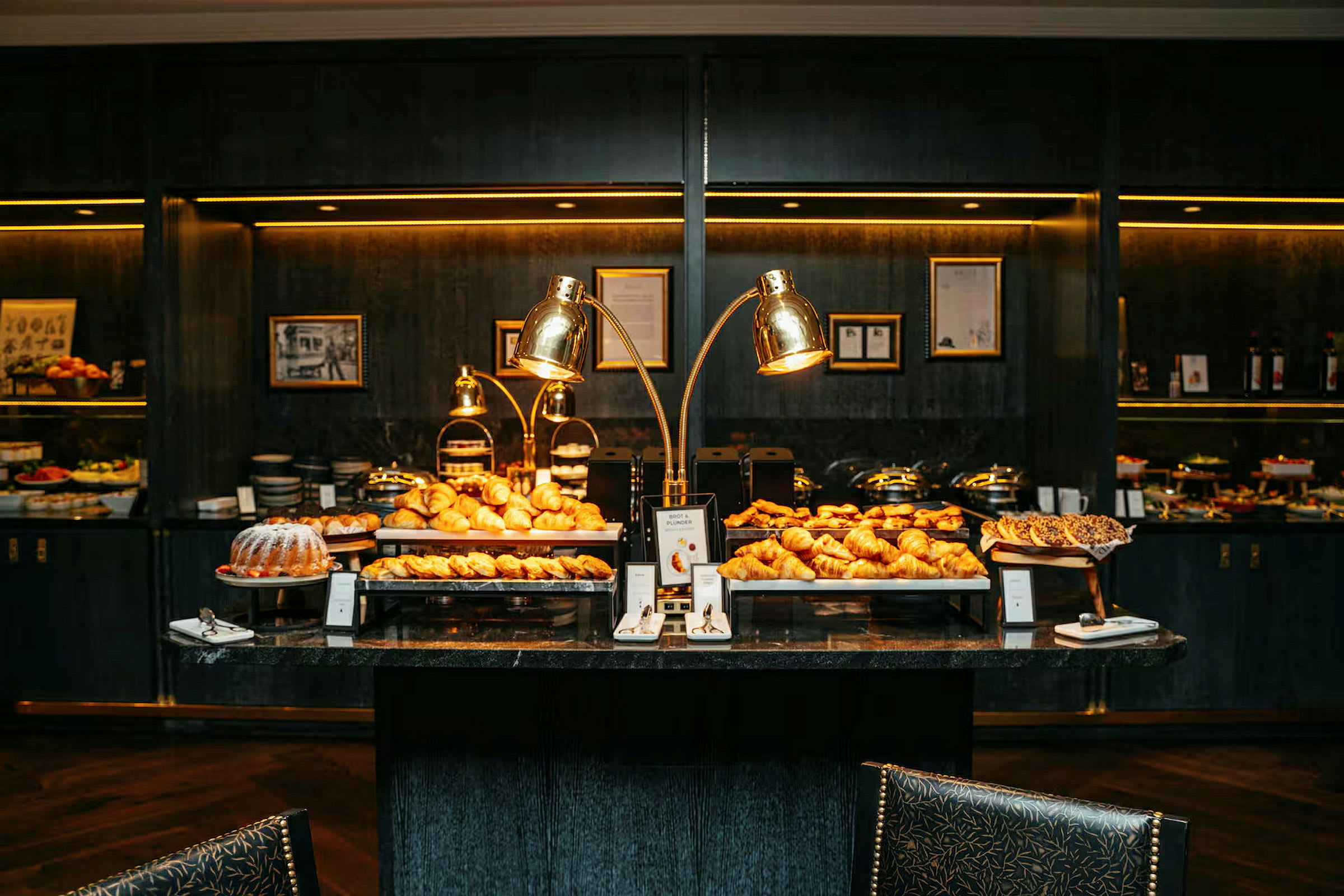 Bilde av en elegant buffet med ulike bakverk og frokostalternativer, arrangert på bord med belysning. (AI-generert tekst)