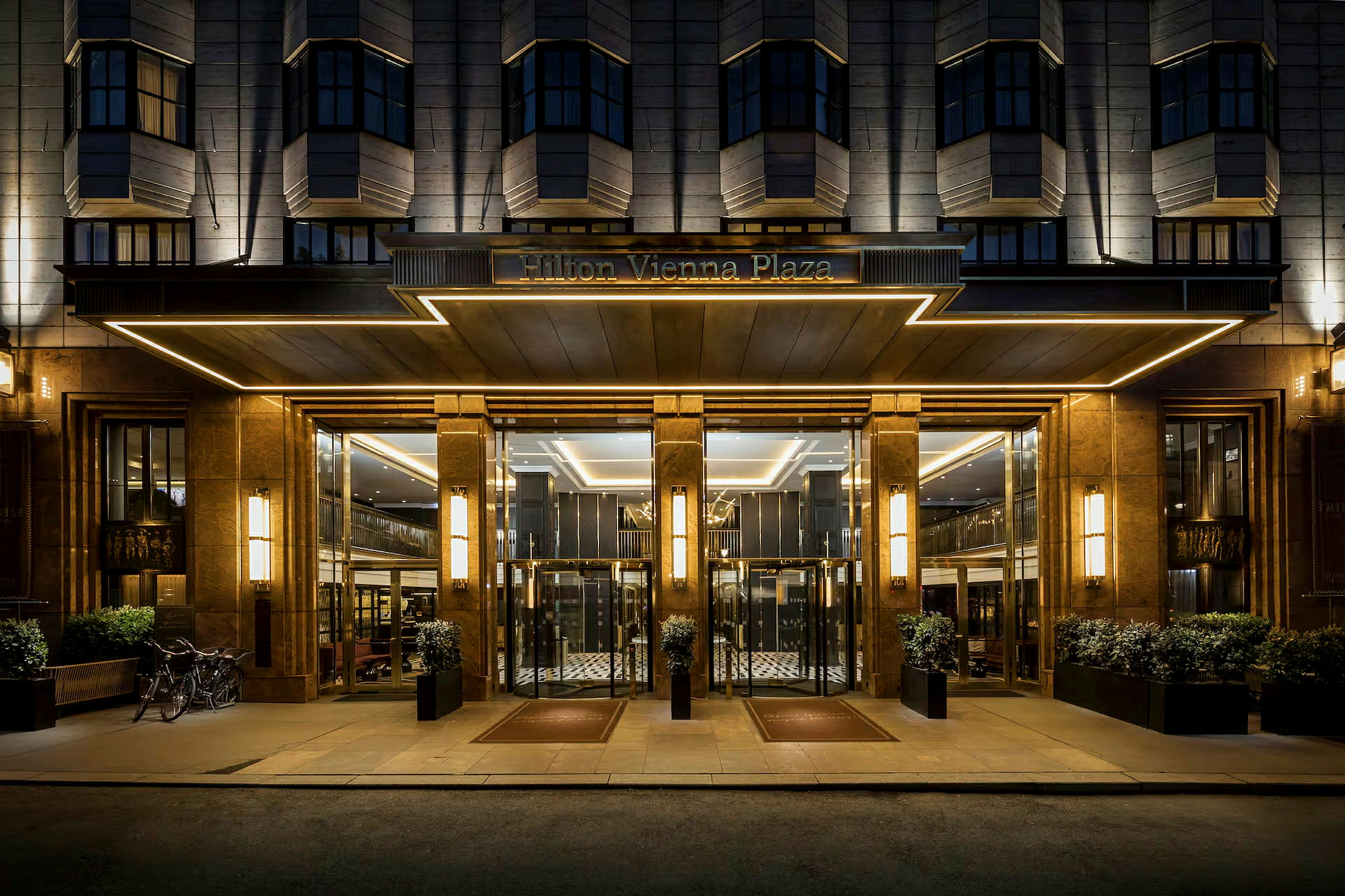 Hotellinngang om kvelden med glassdører og elegant belysning. (AI-generert tekst)