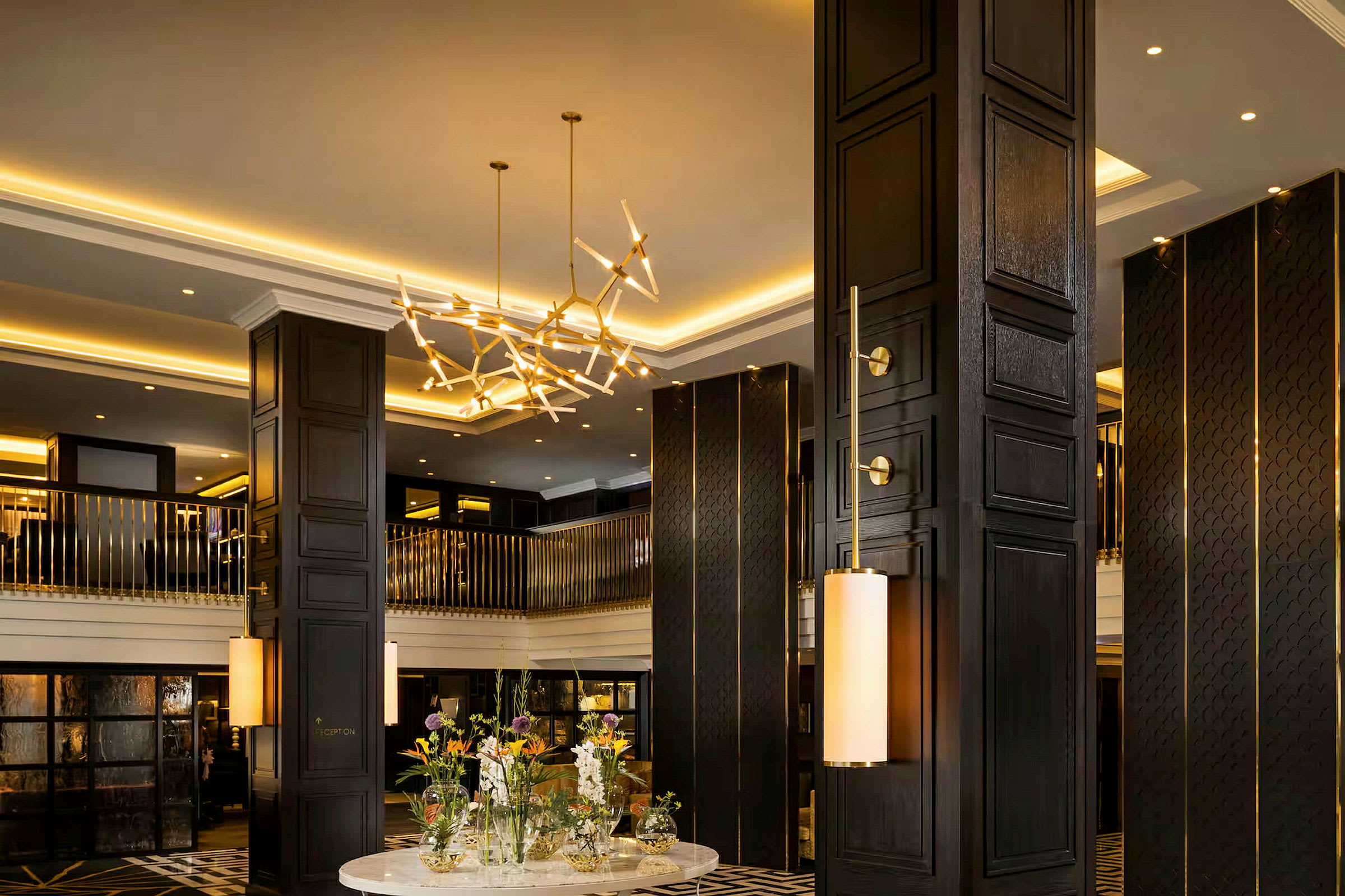 En luksuriøs hotellobby med mørkt trearbeid, elegant belysning og et bord med blomsteroppsatser i midten. (AI-generert tekst)