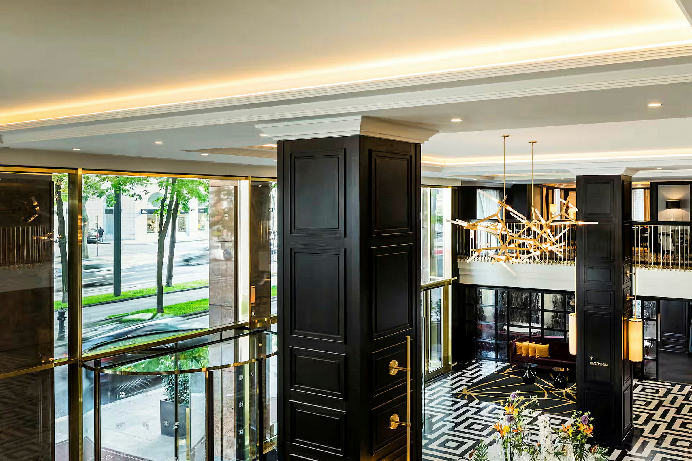 En elegant hotellobby med moderne detaljer, mørke søyler, og store vinduer med utsikt mot gaten utenfor. (AI-generert tekst)