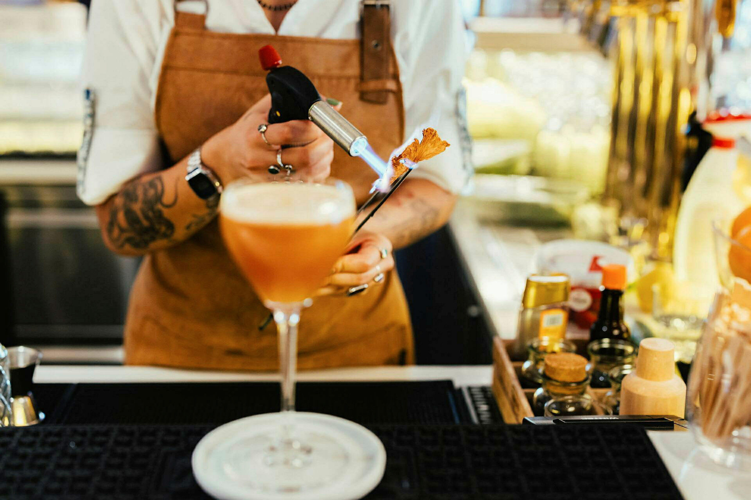 En person holder en brenner og forbereder en cocktail. (AI-generert tekst)