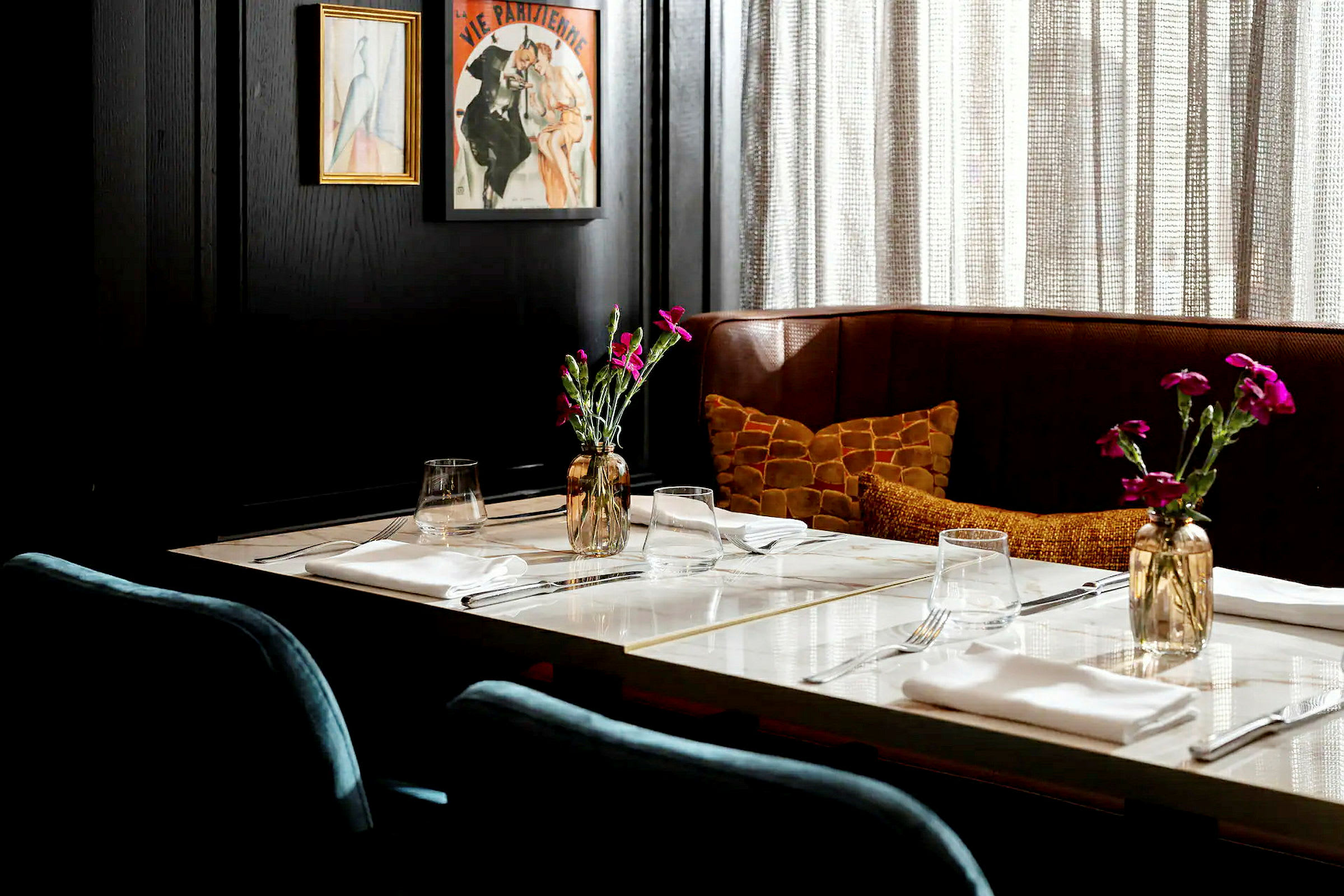 Et elegant dekket bord i en restaurant, med blomster i en vase og kunst på veggen. (AI-generert tekst)