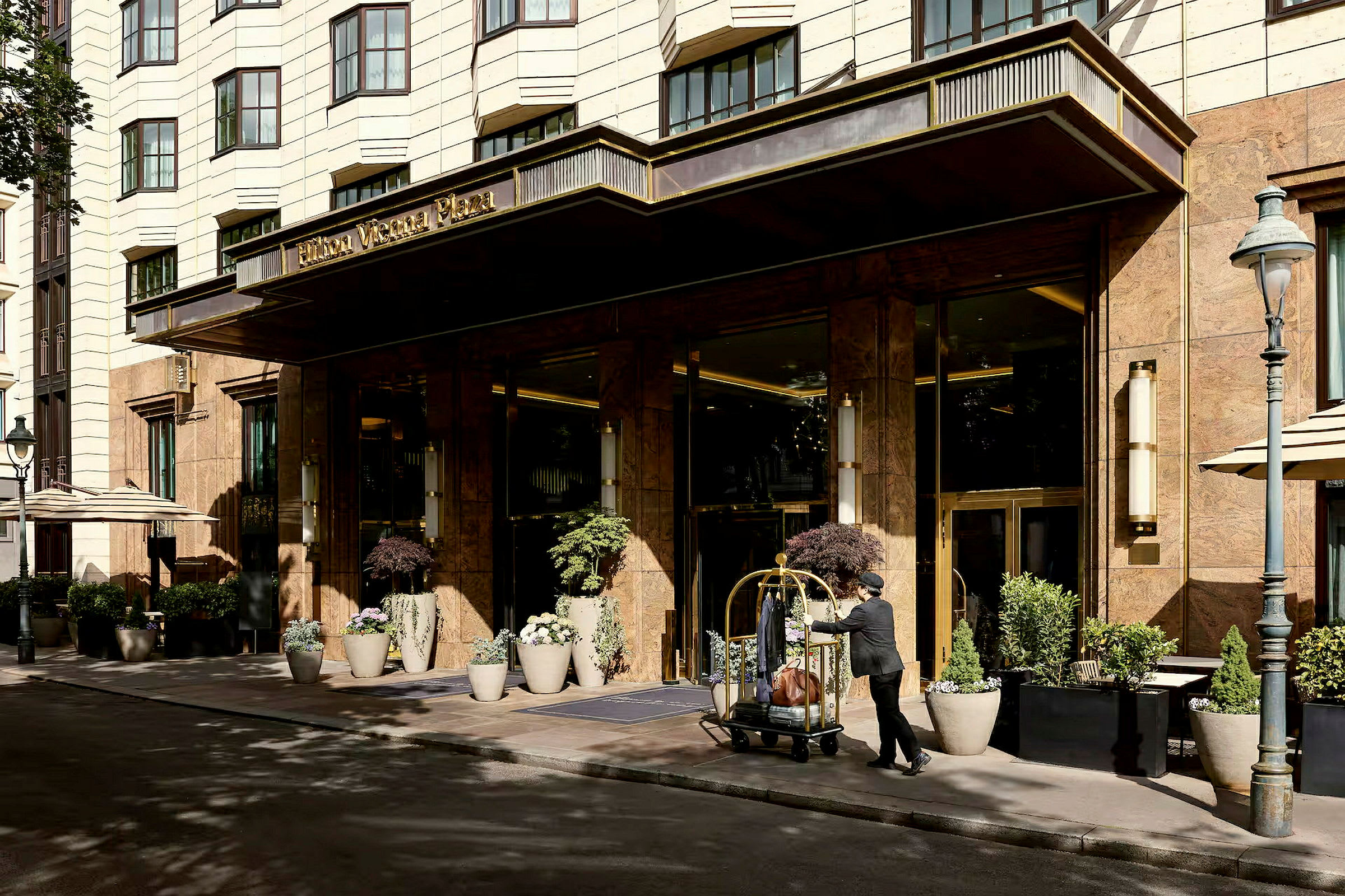 Inngangen til et hotell med en mann som triller en bagasjevogn. (AI-generert tekst)