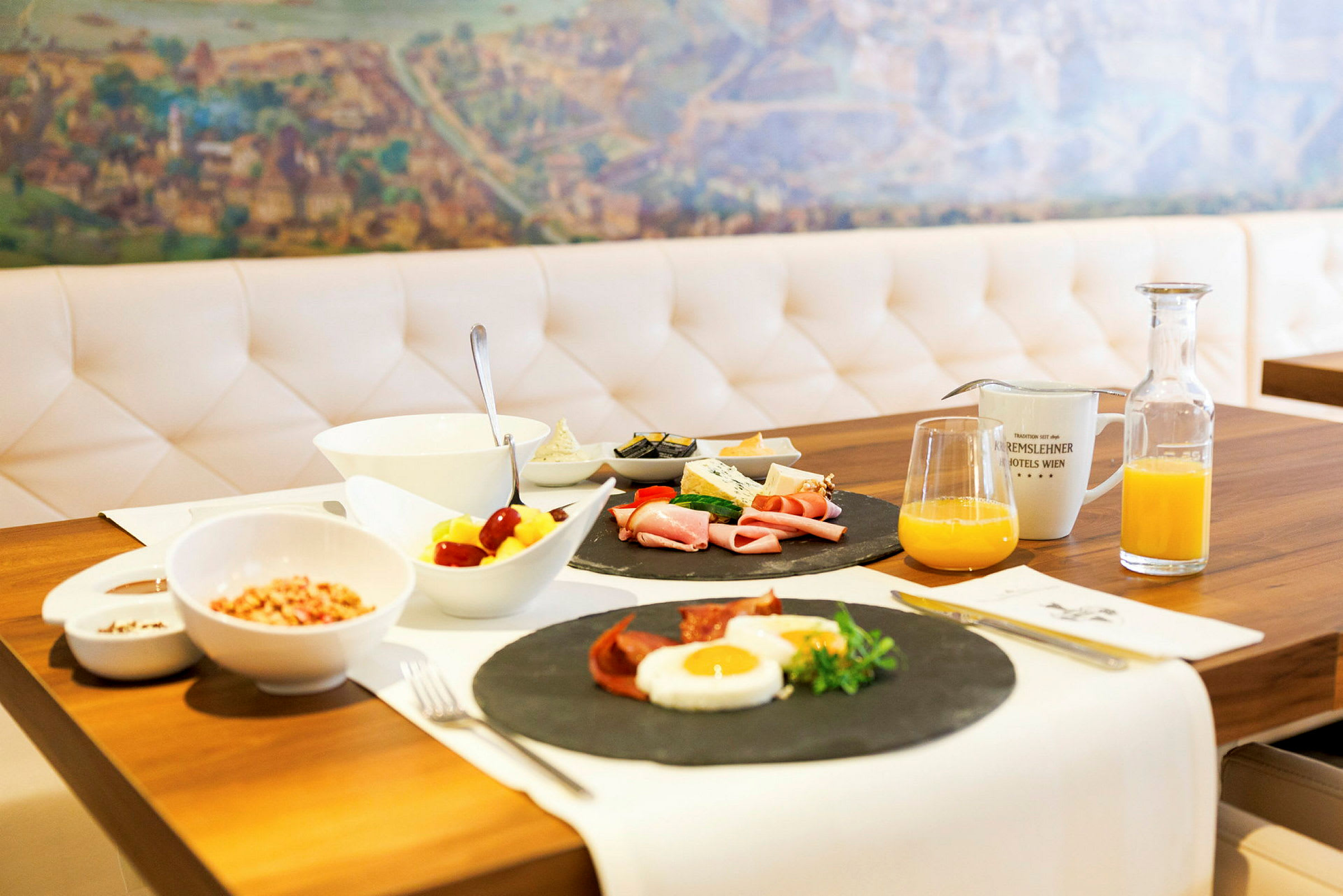 En frokost servert på et bord med diverse retter, speilegg, pålegg og grønnsaker, samt juice og kaffe. (AI-generert tekst)