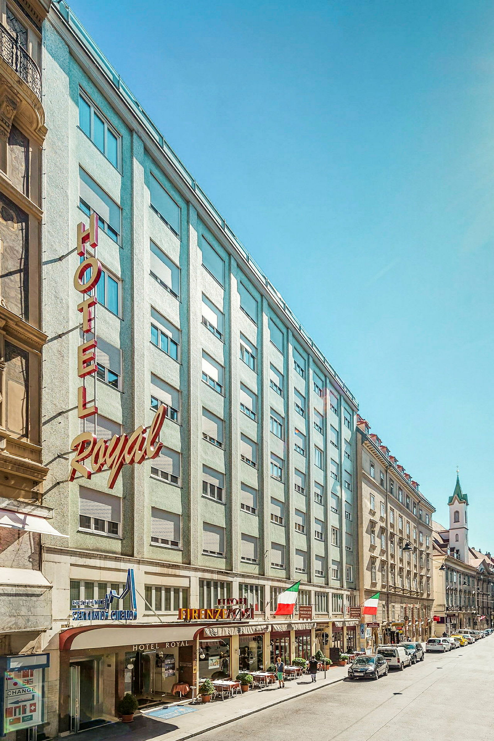 Bilde av en bygate med hotellfasade og bygninger rundt. (AI-generert tekst)