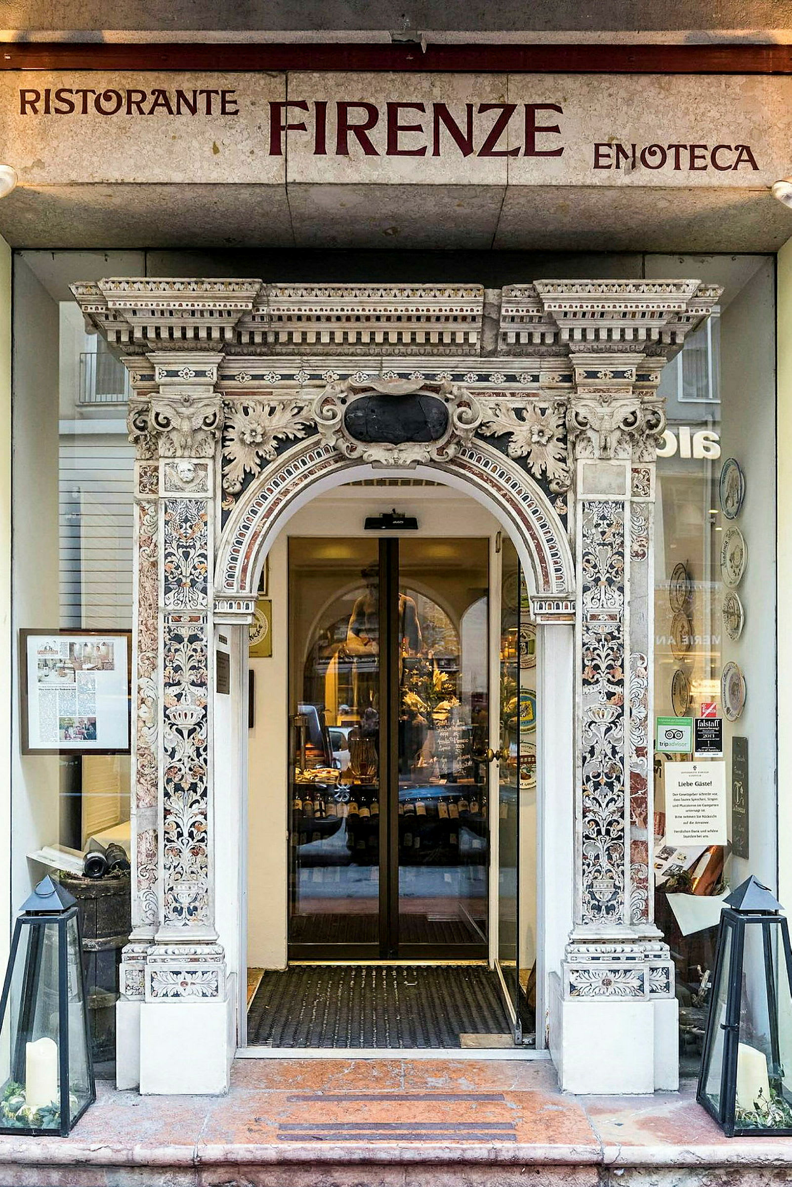 Inngang til en restaurant med dekorativt utsmykket portal og glassdører. (AI-generert tekst)