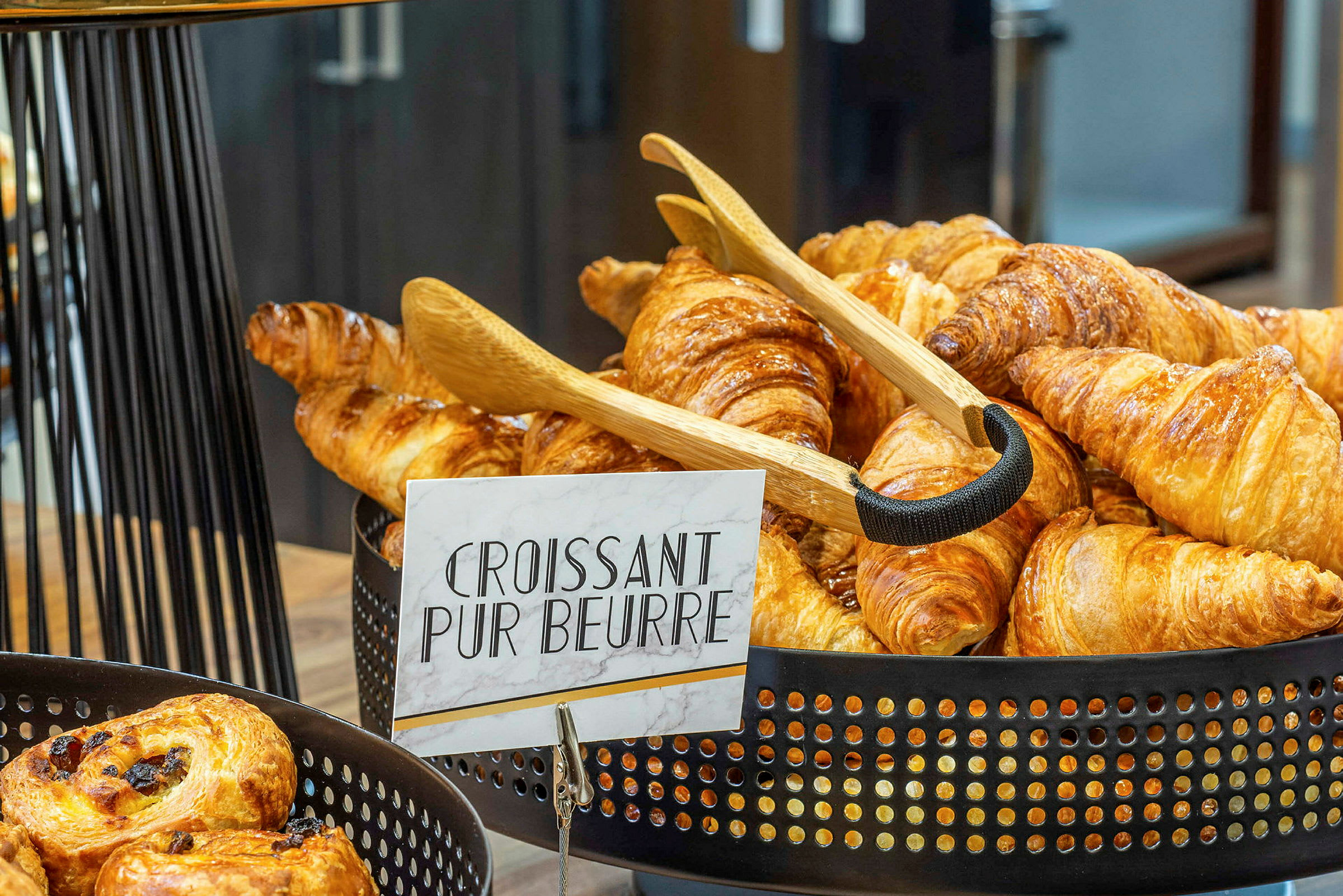 En kurv fylt med nystekte croissanter med et skilt som sier 'Croissant Pur Beurre'. (AI-generert tekst)