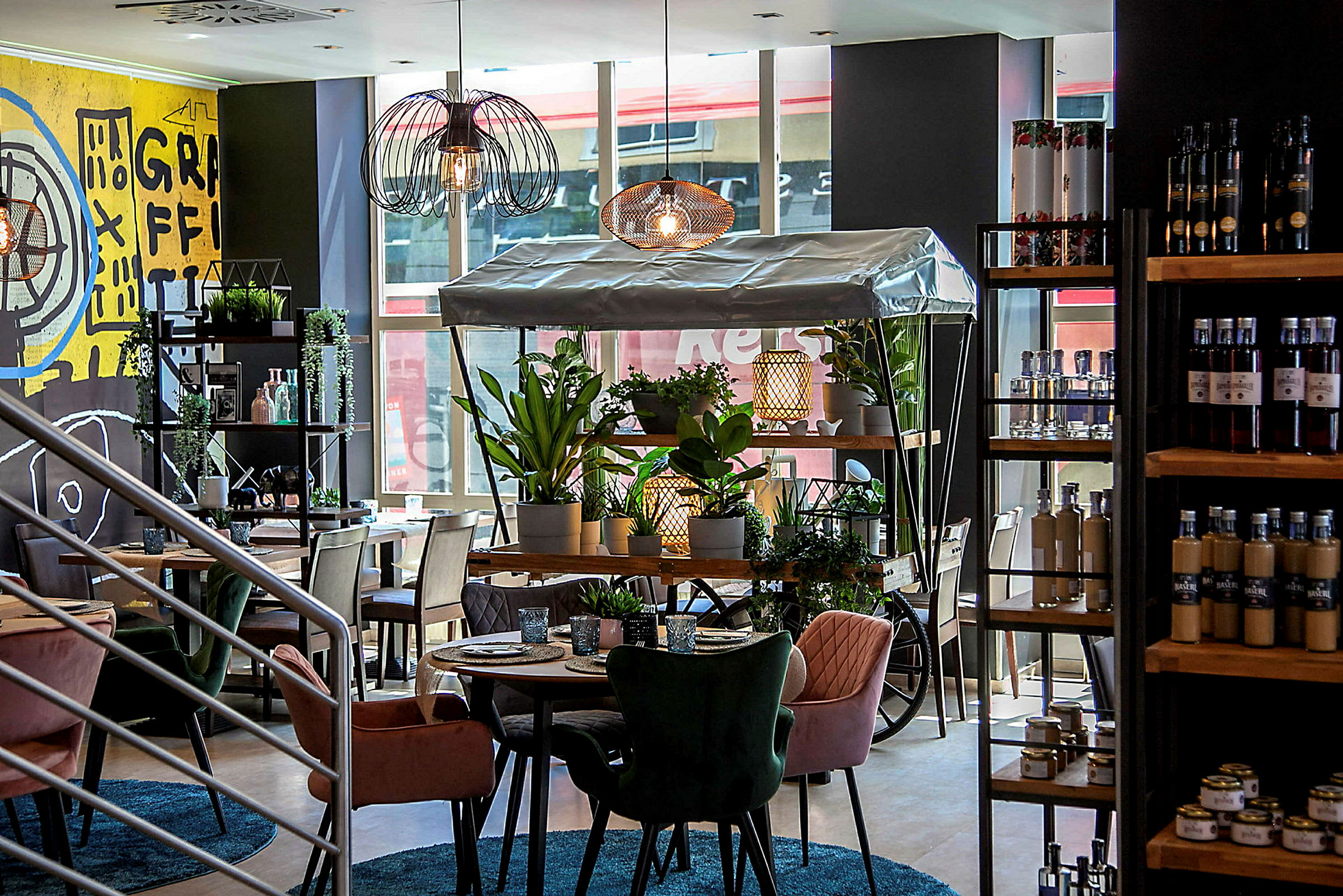 Interiør av en moderne kafé med fargerike stoler, grønne planter og en dekorativ plantevogn. (AI-generert tekst)