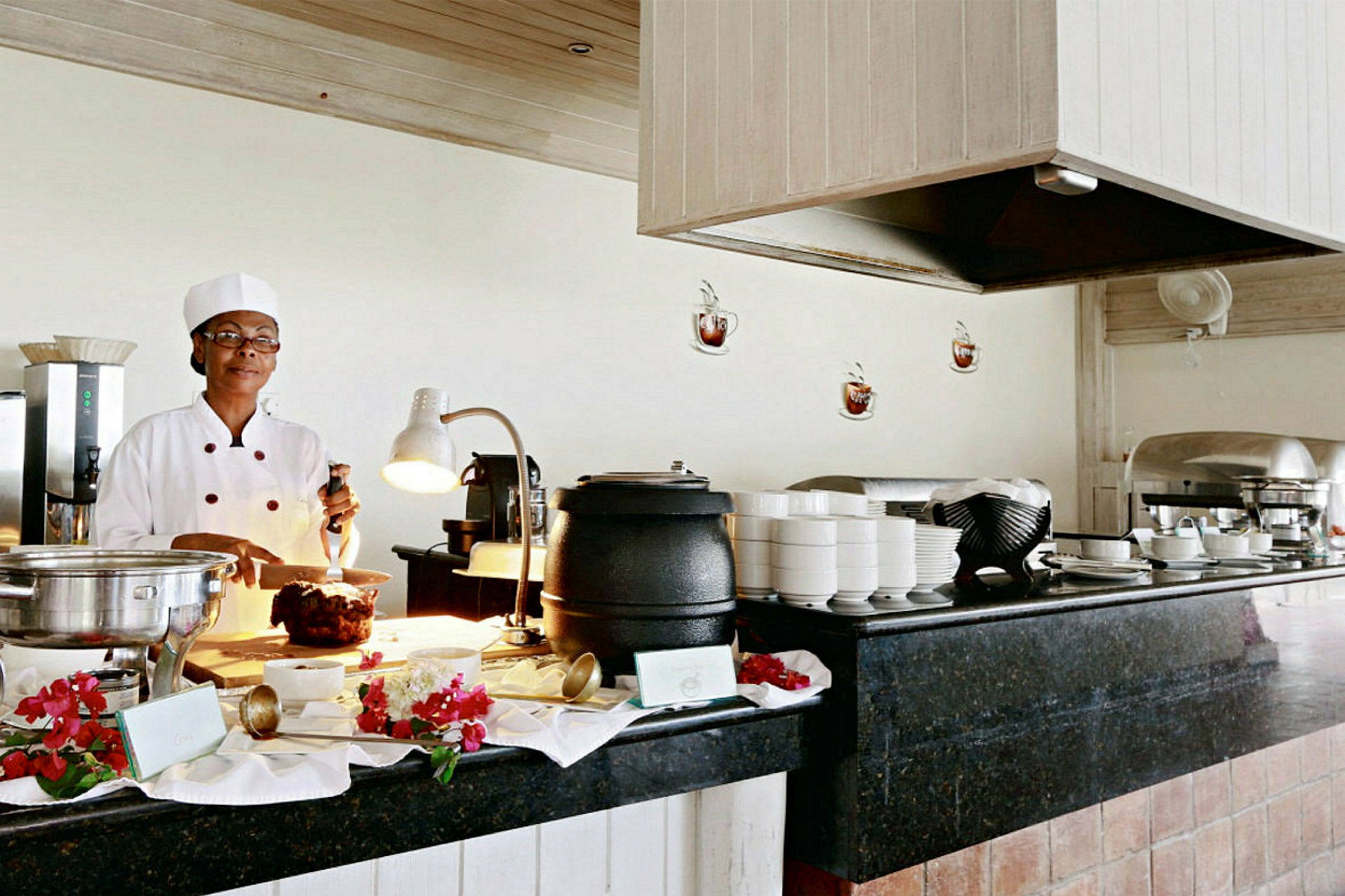 Bufféområde med kokk som tilbereder mat, omgitt av serveringsutstyr og dekorasjoner. (AI-generert tekst)