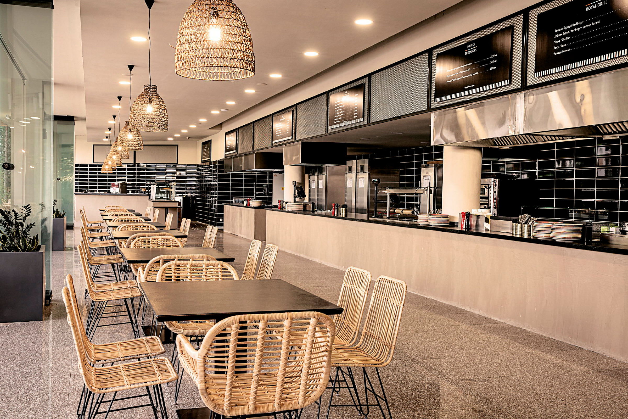 Moderne restaurantmiljø med naturfargede stoler og bord foran et åpent kjøkken. (AI-generert tekst)