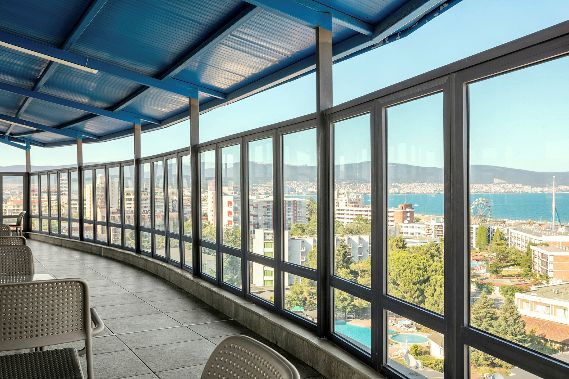 Interiør med en innglasset veranda med utsikt over en by og havet. (AI-generert tekst)