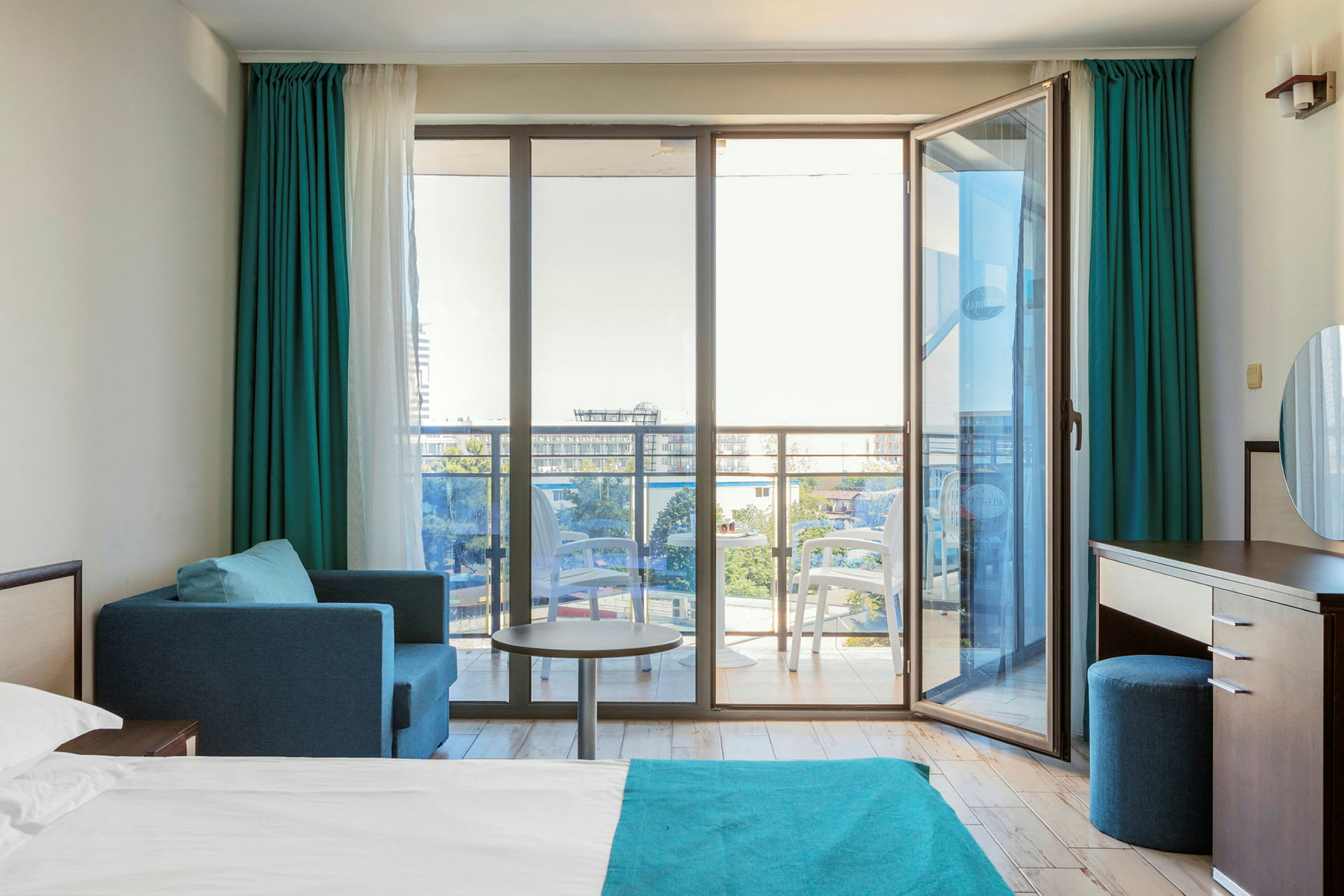 Moderne hotellrom med en seng, sittegruppe og glassdører ut til en balkong. (AI-generert tekst)