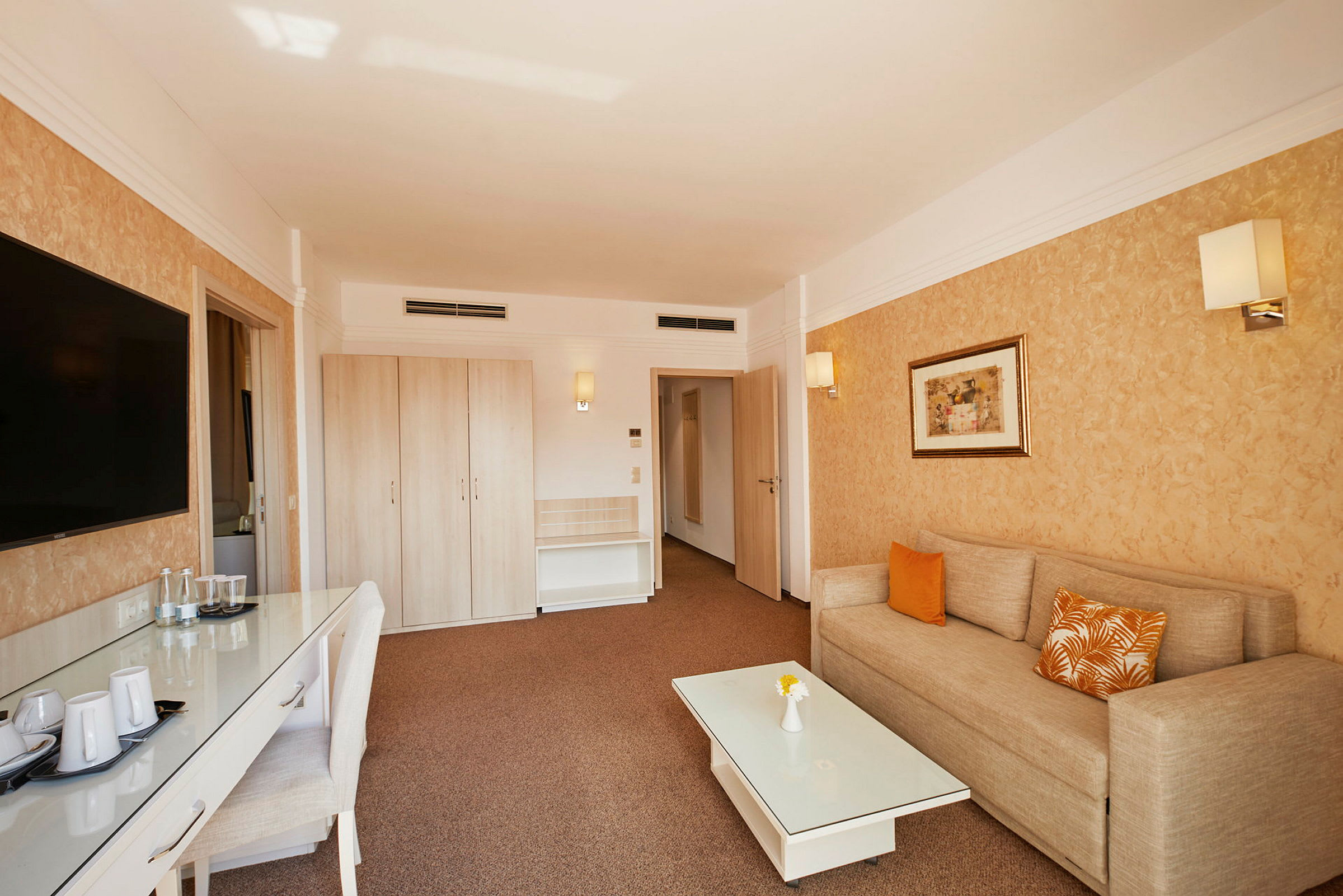 Hotellrom med sofa, bord og garderobe. (AI-generert tekst)