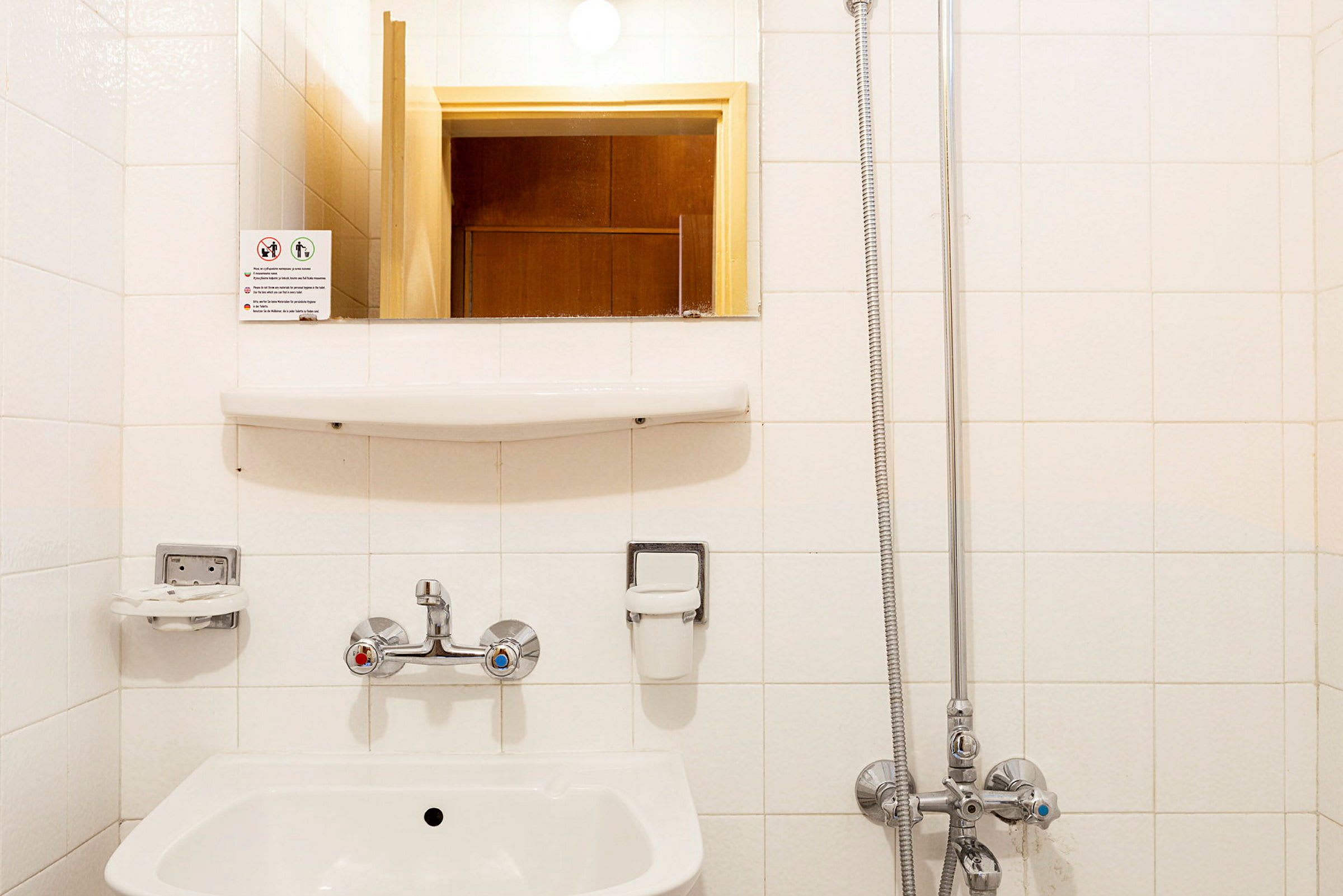 Et badespeil over en vask med kran og avløp for dusj. (AI-generert tekst)