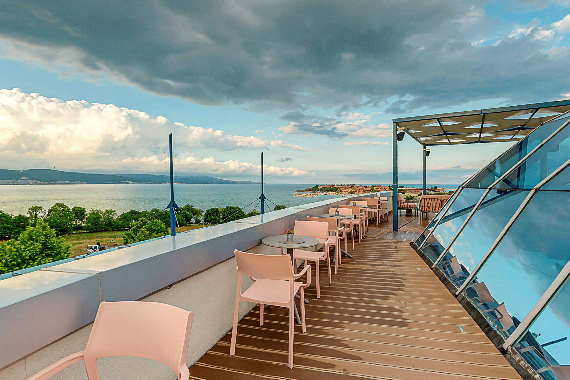 Takterrasse med serveringsbord og stoler, med utsikt over hav og landskap. (AI-generert tekst)