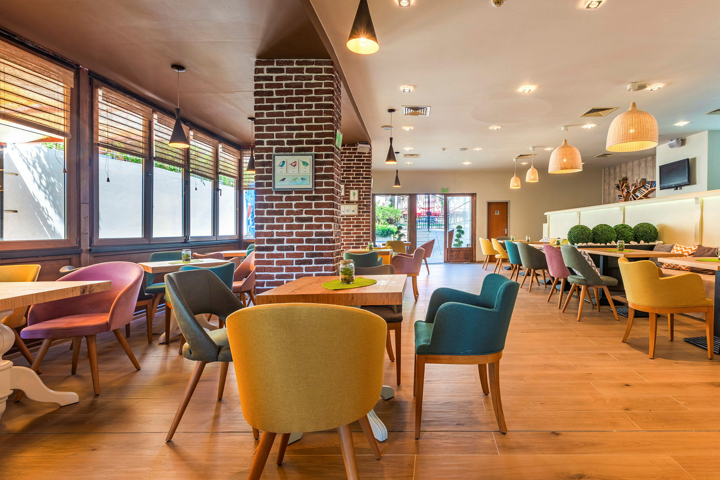 Interiør av en moderne restaurant med fargerike stoler og trebord. (AI-generert tekst)