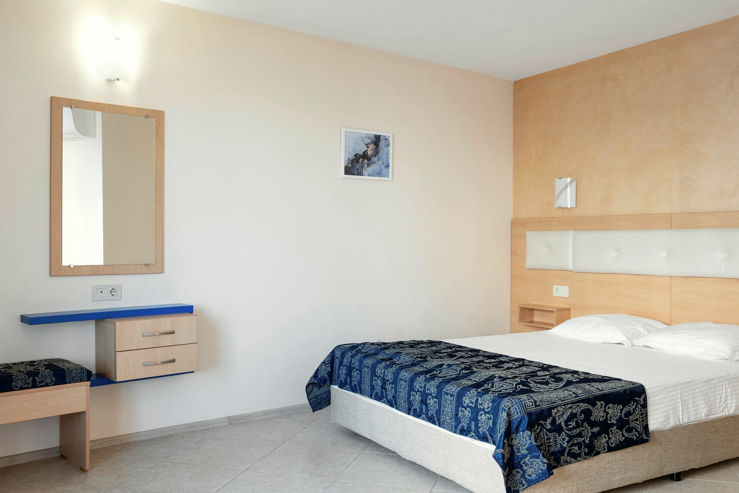 En hotellseng med blått mønstret sengeteppe i et moderne rom. (AI-generert tekst)