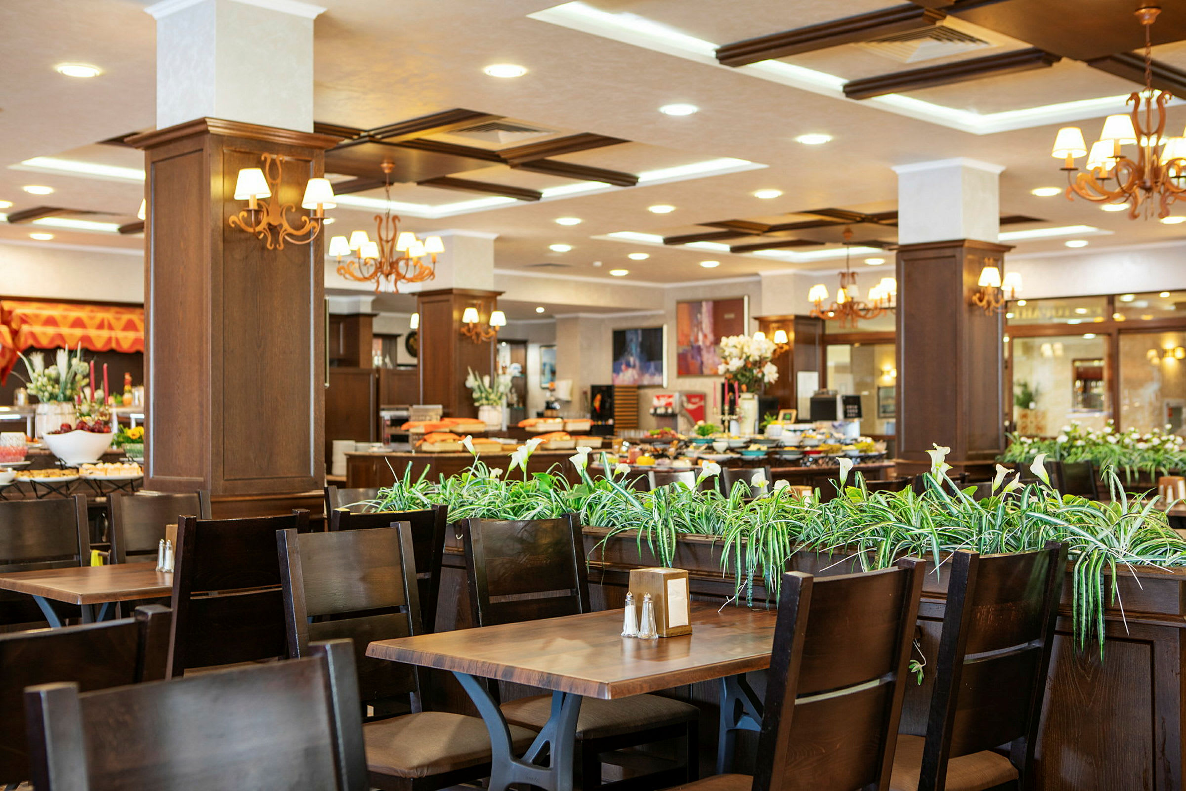 Interiør av en restaurant med mørke trebord og stoler, grønne planter som dekorasjon. (AI-generert tekst)