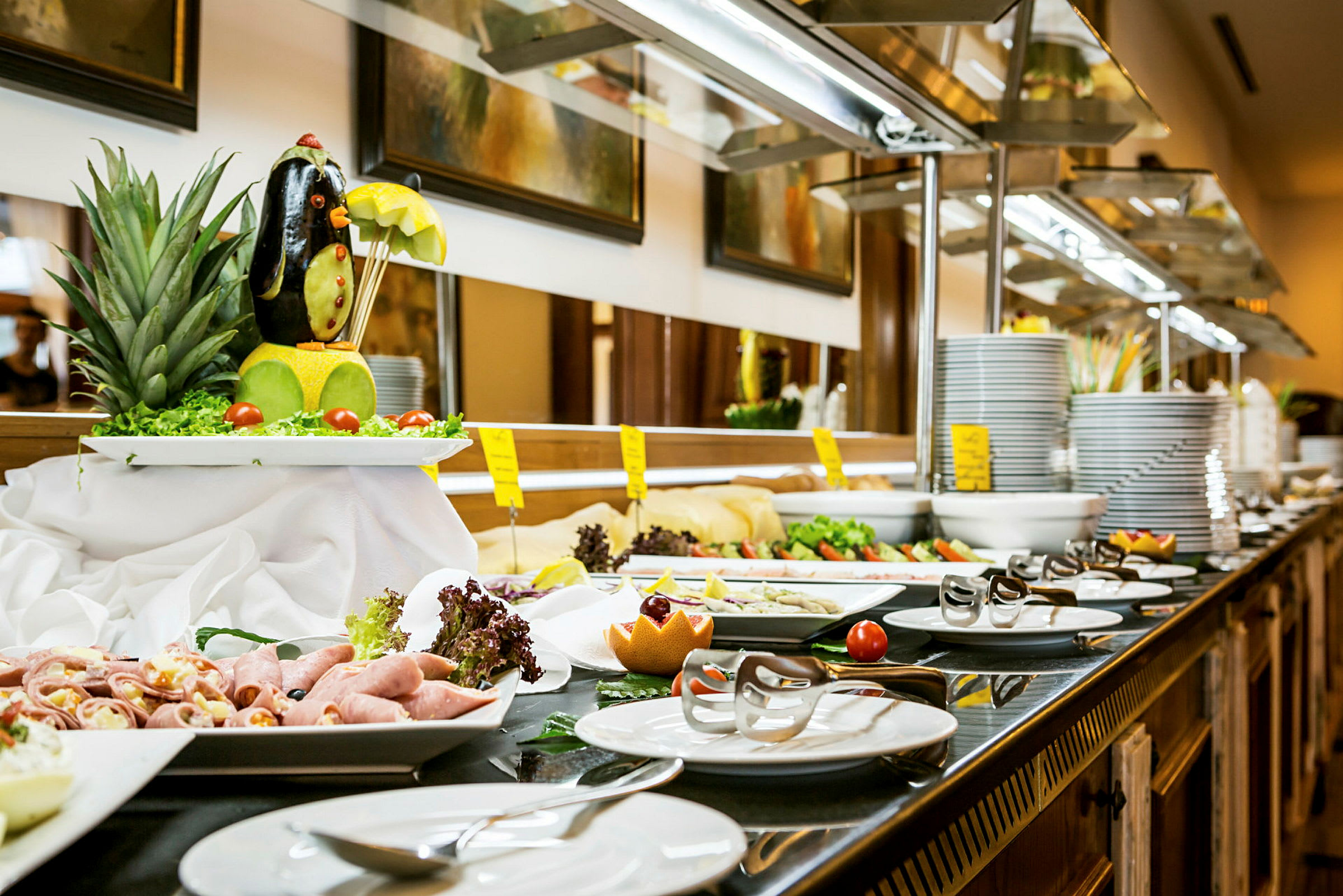 Buffetbord med forskjellige retter inkludert salat, kaldmat og dekorert frukt. (AI-generert tekst)