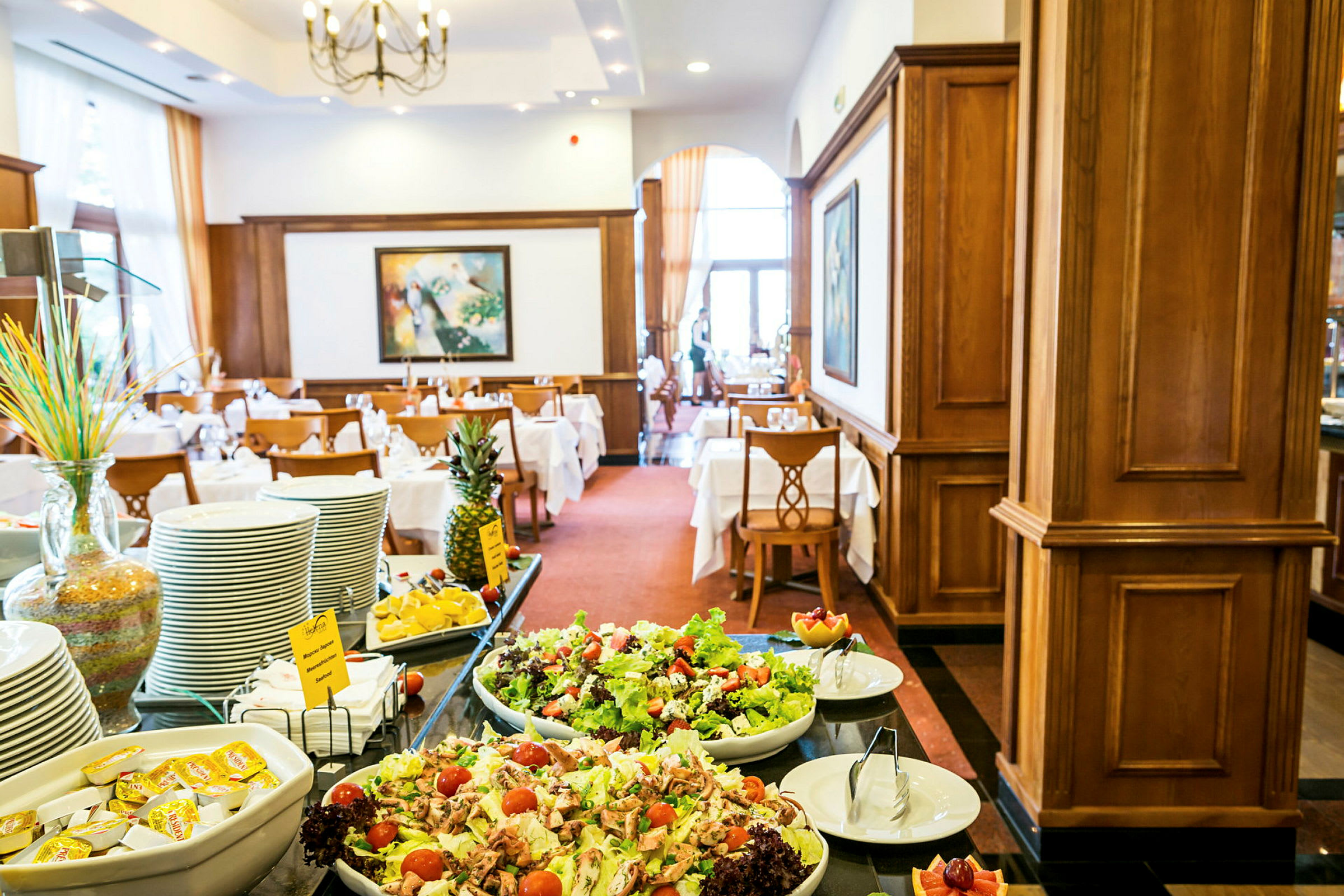 Buffetbord med salat, frukt og servise i en elegant innredet restaurant. (AI-generert tekst)