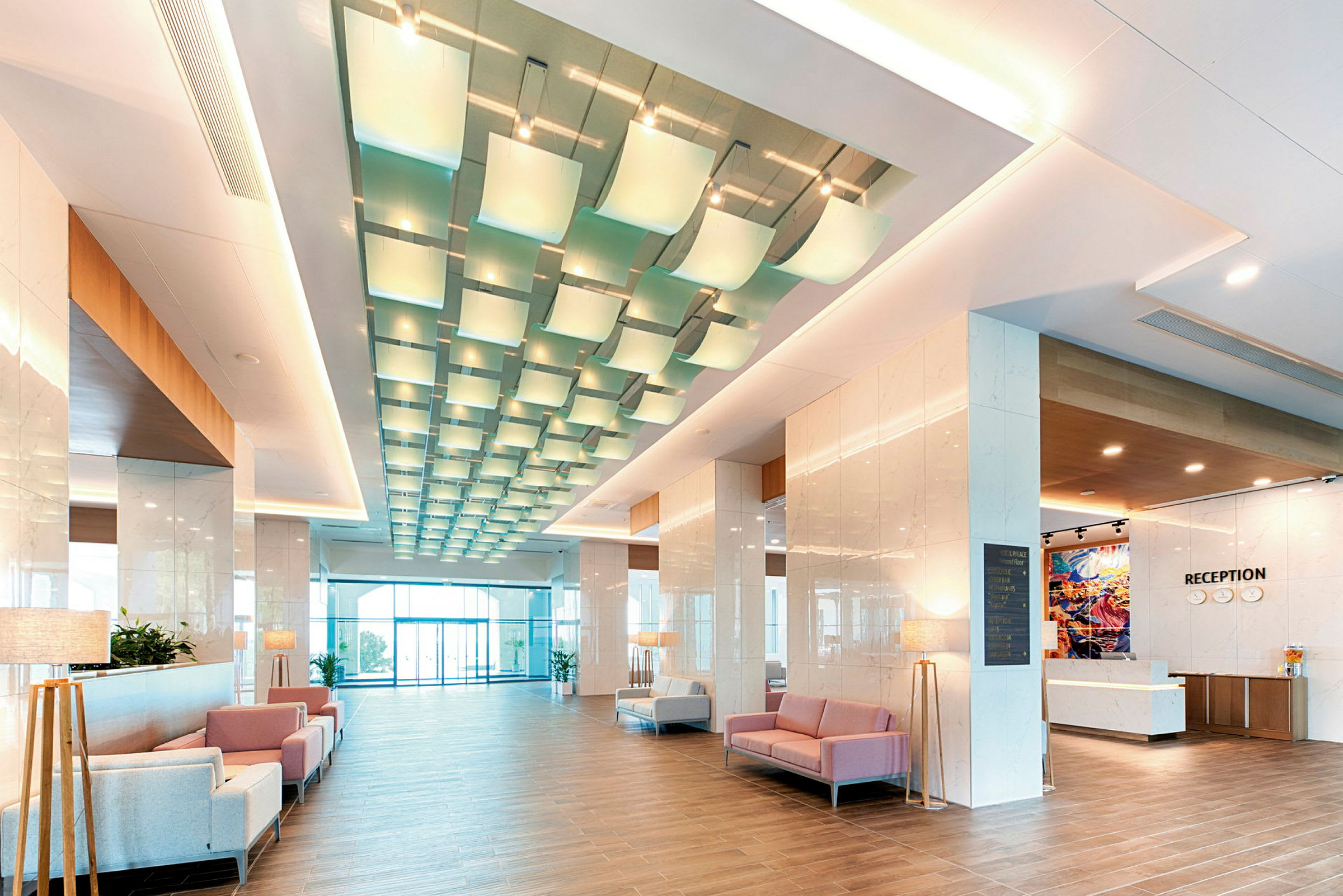 Et bilde av en moderne hotellobby med sitteplasser, resepsjon og dekorativ belysning. (AI-generert tekst)
