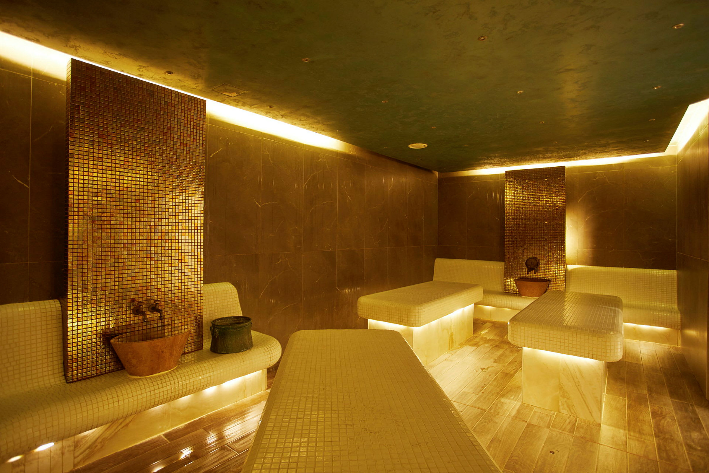 Innendørsbilde av et tyrkisk hamam med mosaikkvegger og opplyste marmorbenker. (AI-generert tekst)