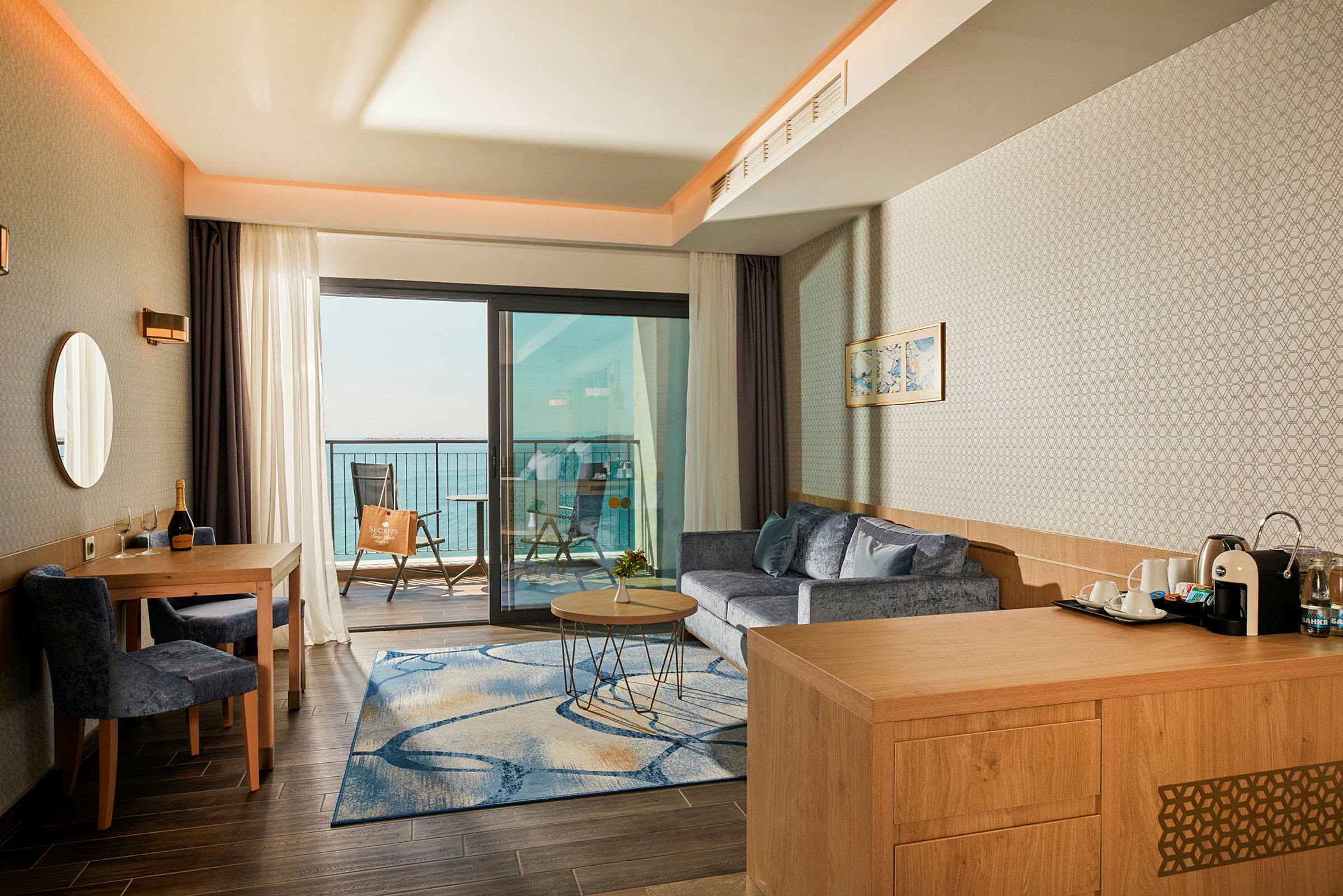 Hotellrom med sittegruppe og utsikt over havet fra balkongen. (AI-generert tekst)