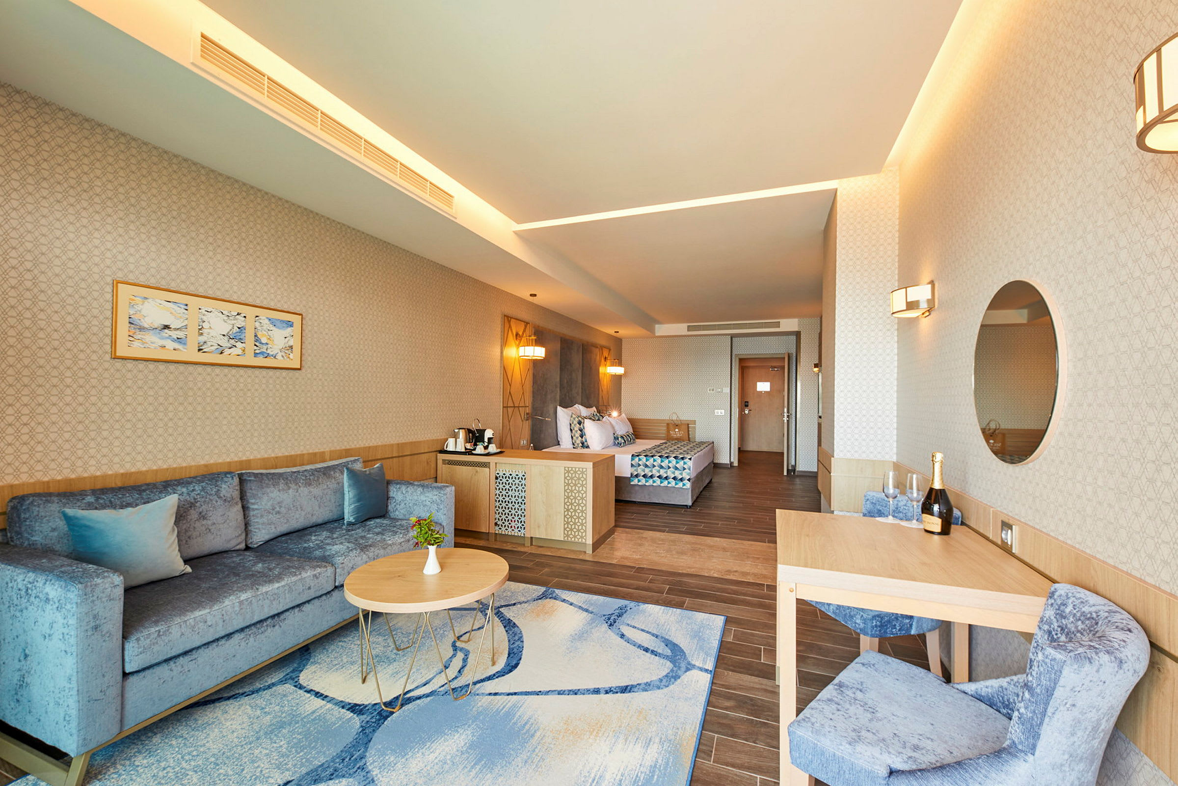 Interiør av et hotellrom med en sofa, sofabord, spisebord og en seng. (AI-generert tekst)