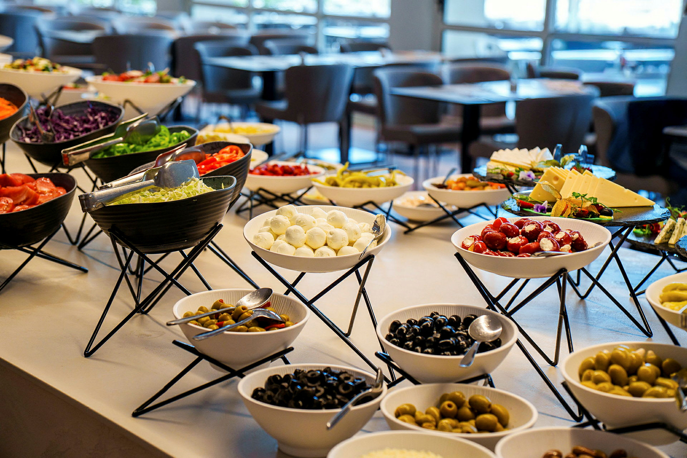 En buffé med forskjellige boller fylt med grønnsaker, oster og oliven i en restaurant. (AI-generert tekst)