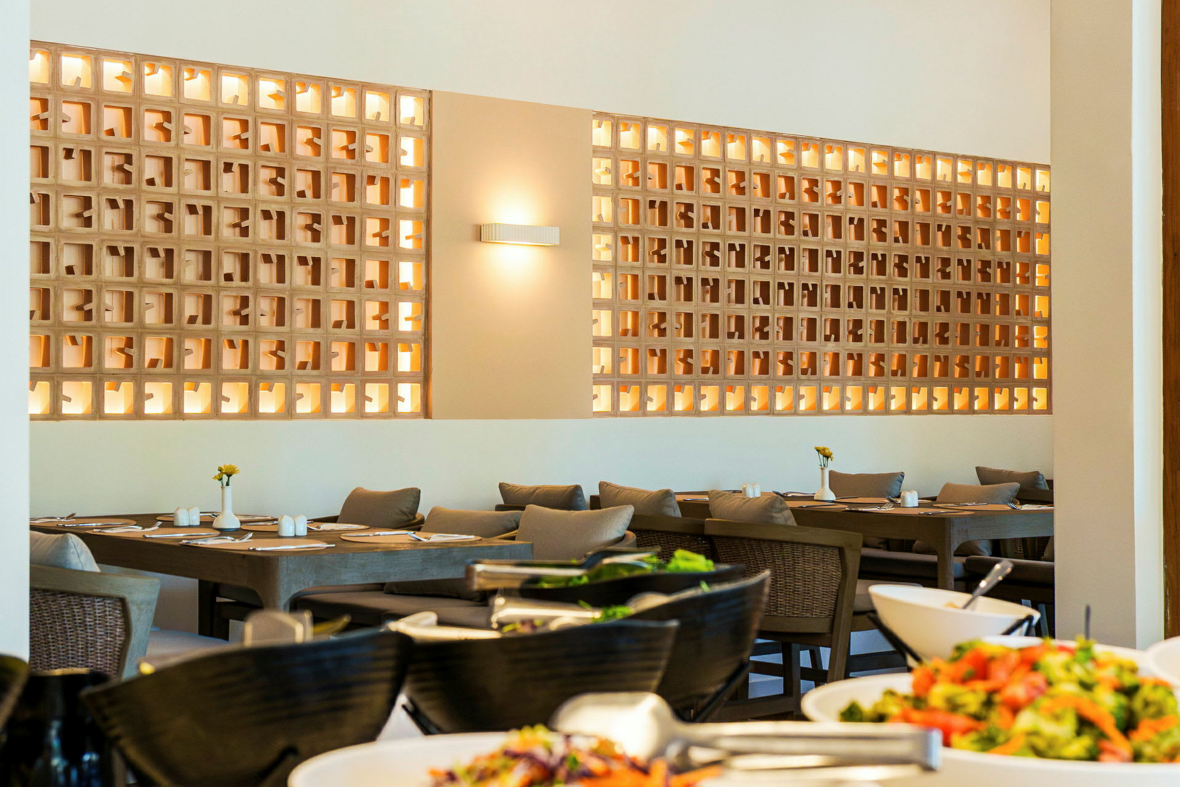 Et opplyst spisebord med stoler og dekorativ vegg i en restaurant. (AI-generert tekst)