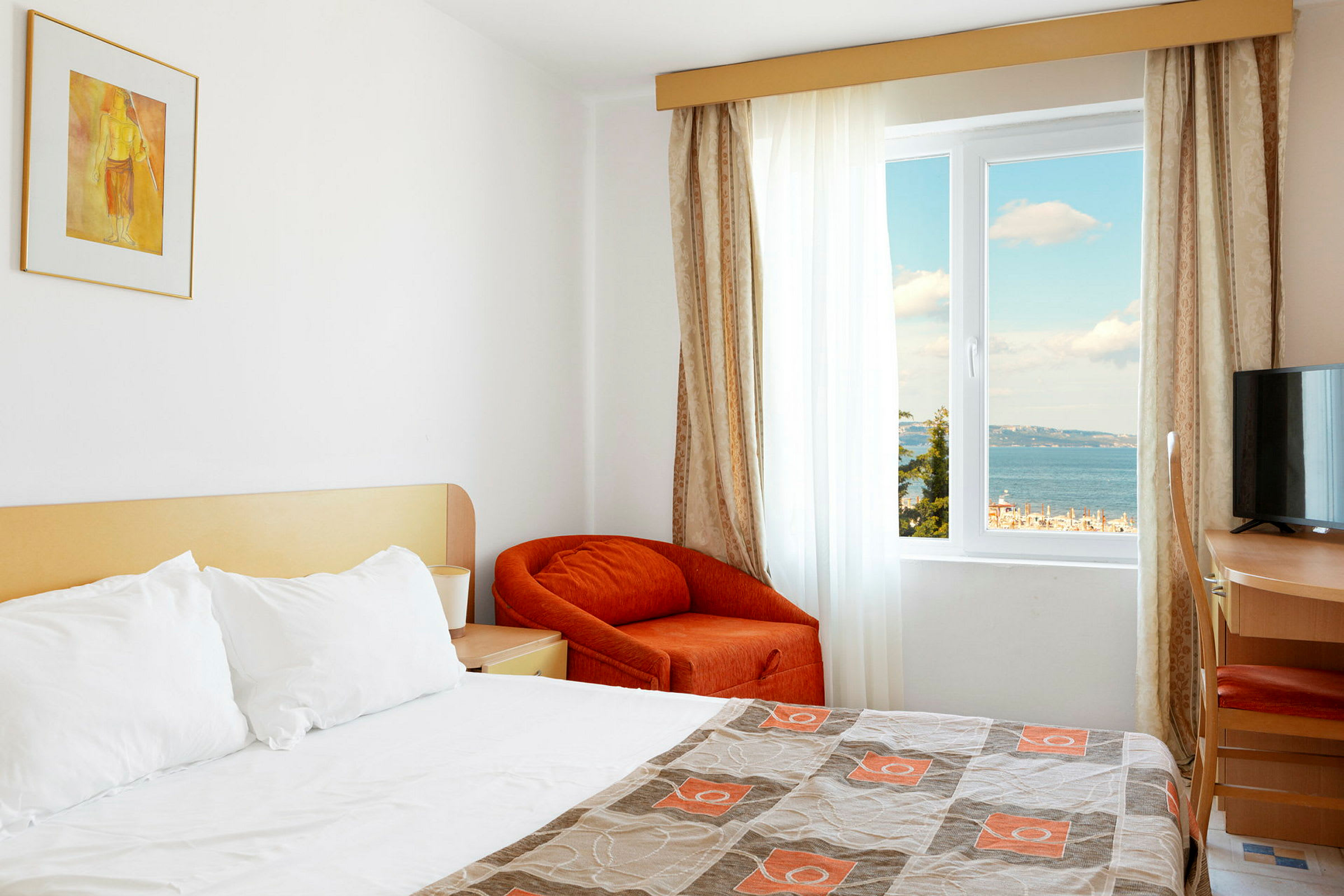 Hotellrom med en oppredd seng og utsikt over havet gjennom vinduet. (AI-generert tekst)