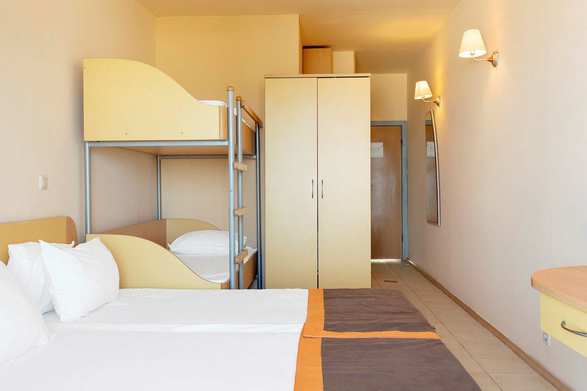 Hotellrom med dobbeltseng, køyeseng og garderobe. (AI-generert tekst)