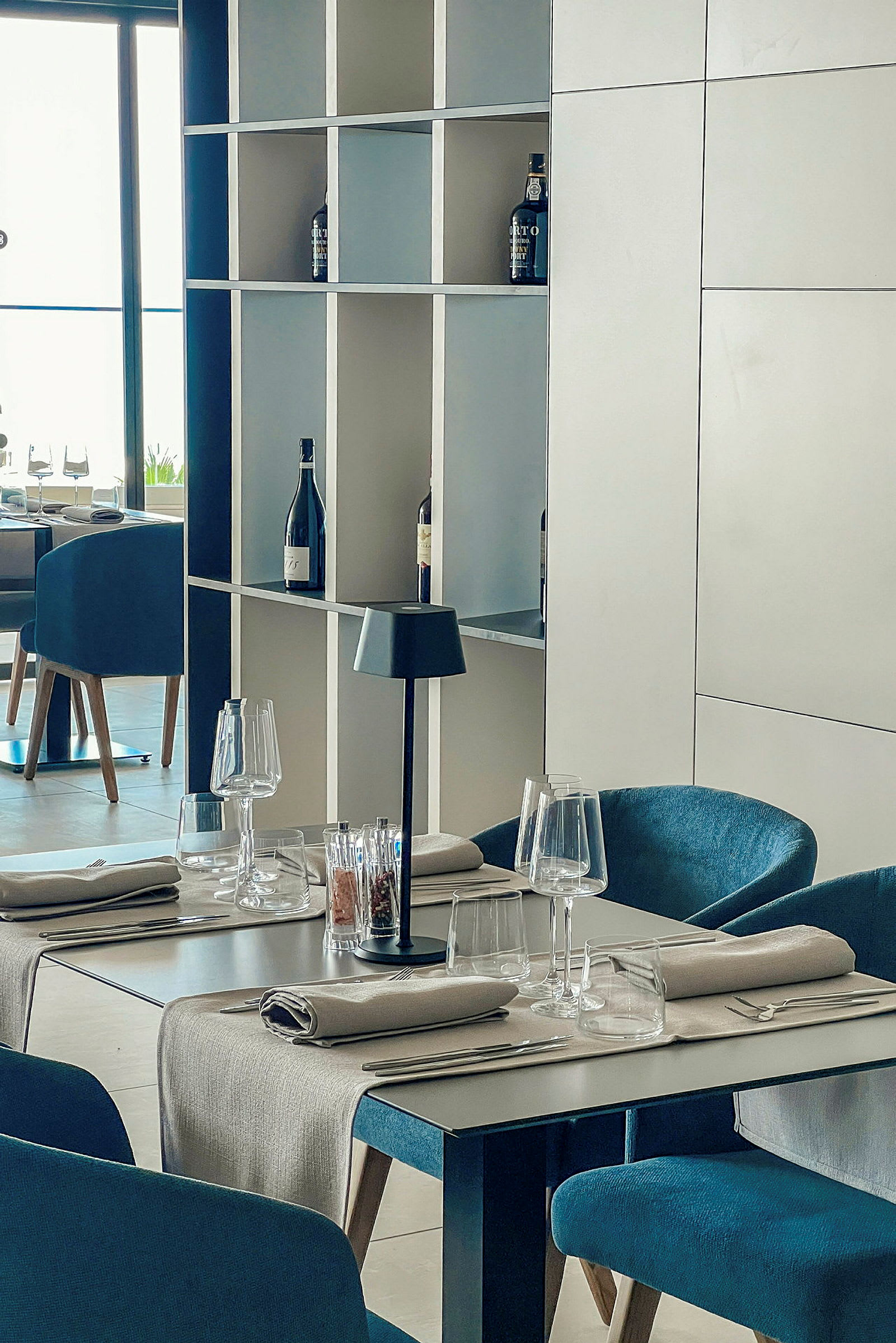 Restaurantbord med borddekking og hyller med vinflasker. (AI-generert tekst)