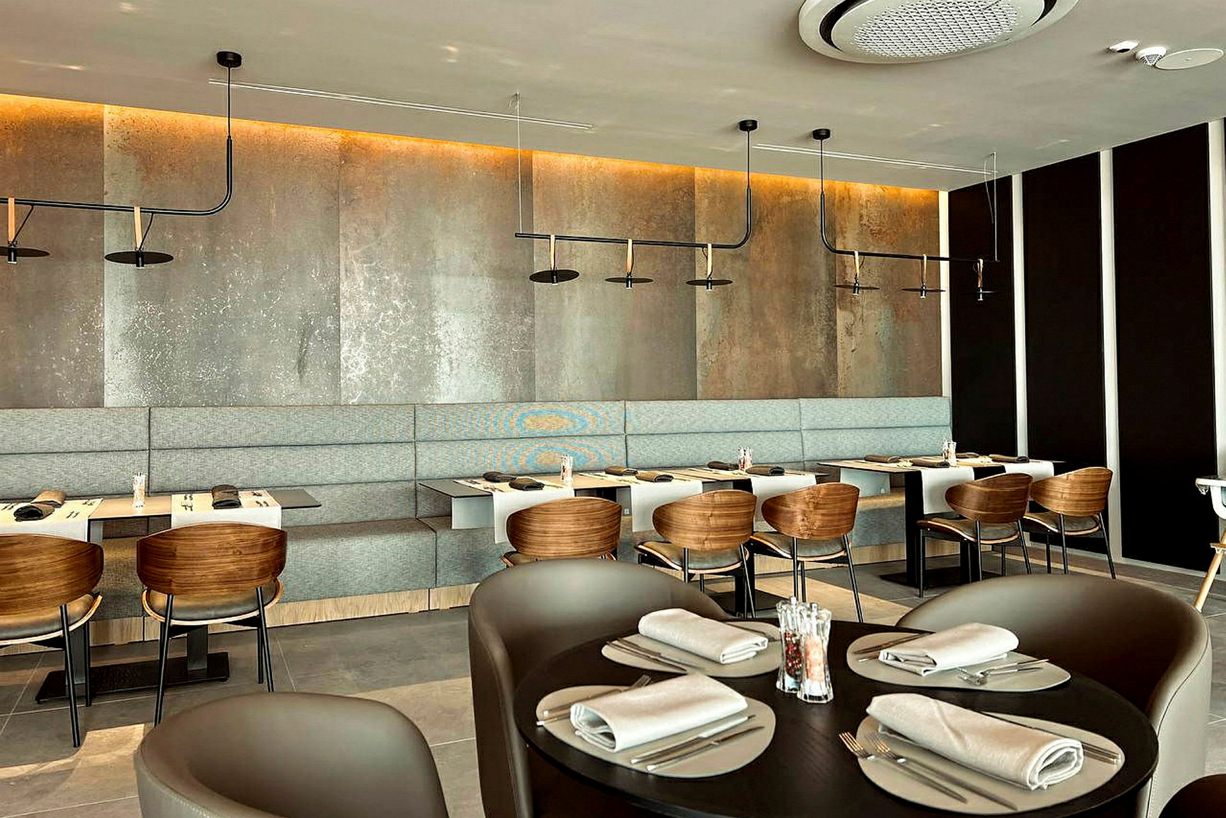 En moderne restaurant med bord, stoler og en benkesete langs veggen. (AI-generert tekst)
