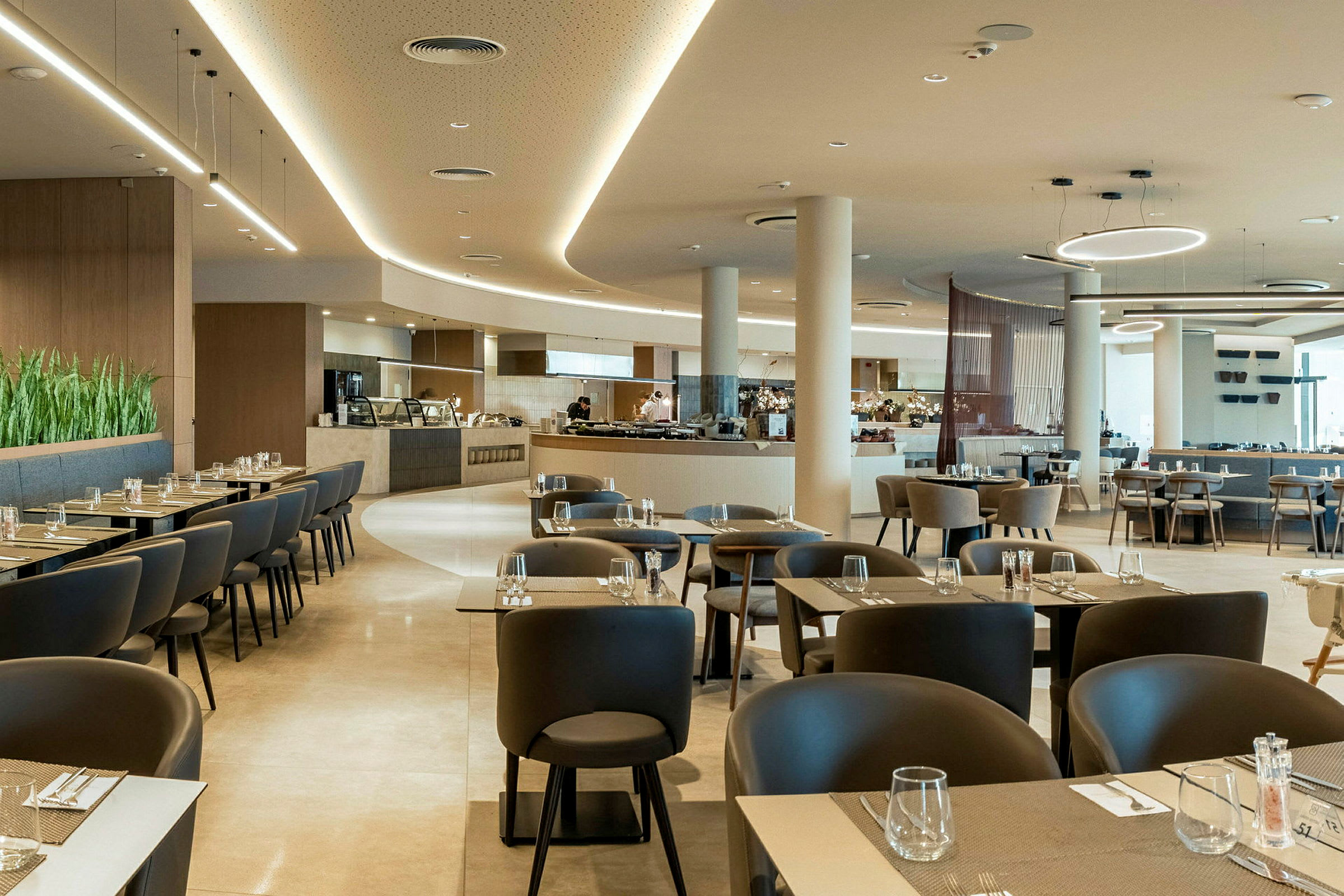 Moderne og lyst innredet restaurantområde med bord og stoler. (AI-generert tekst)