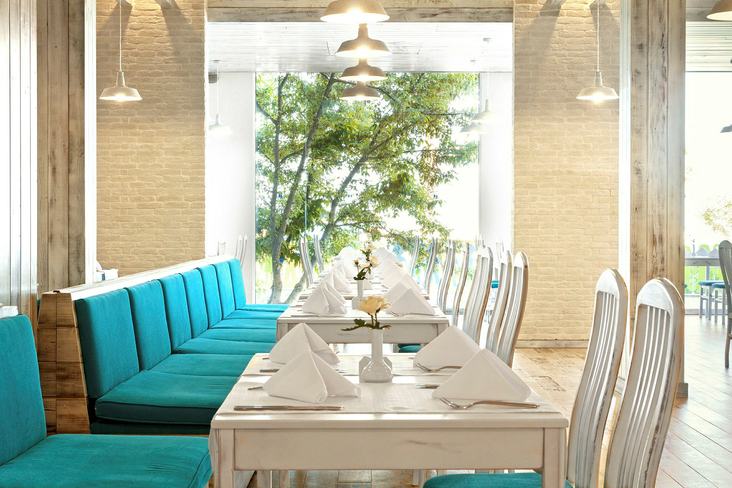 Restaurant med oppdekkede bord og turkise sofaer. (AI-generert tekst)