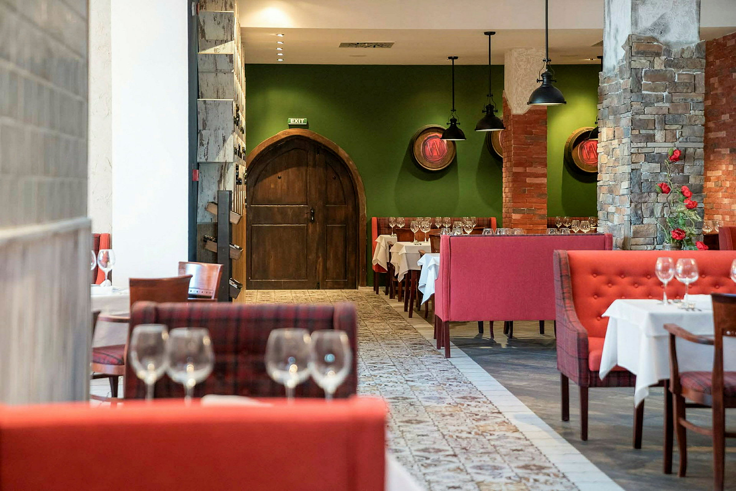 Restaurantinteriør med rødt sittegruppe, grønne vegger og gamle tredører. (AI-generert tekst)