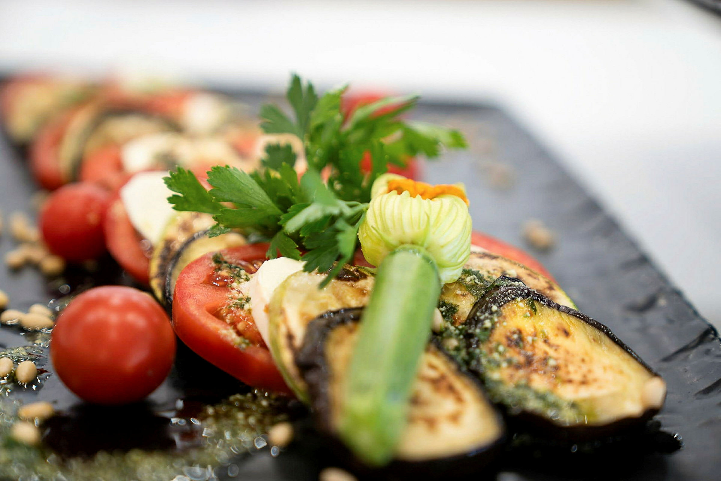 En tallerken med stekt aubergine, tomat og ferske urter. (AI-generert tekst)